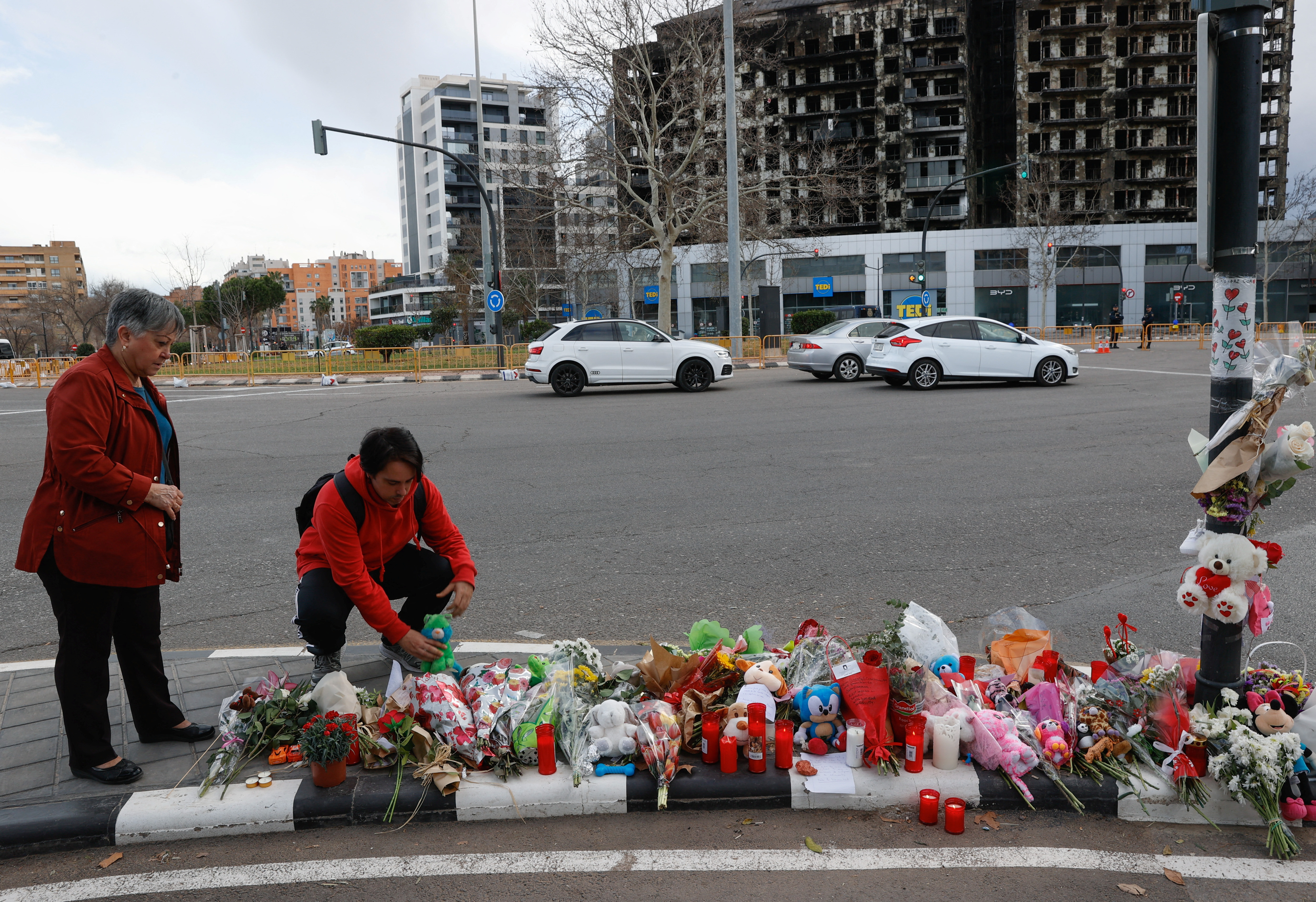 A man places a stuffed toy in a makeshift memorial near the building that caught fire, in Valencia