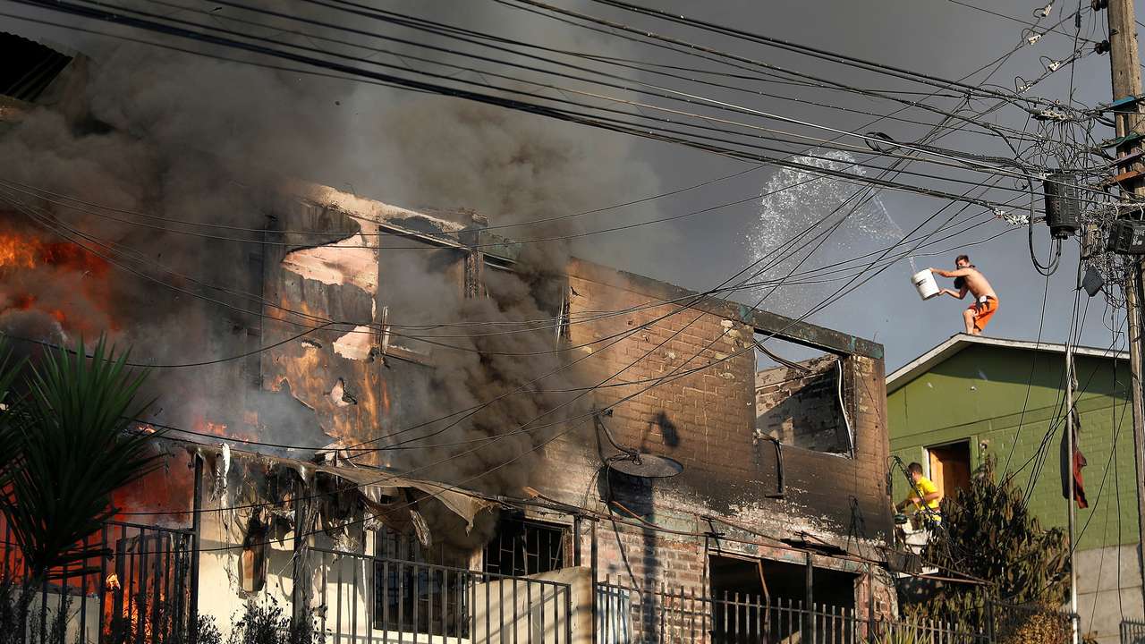 People try to extinguish a fire burning a house during the spread of wildfires in Vina del Mar