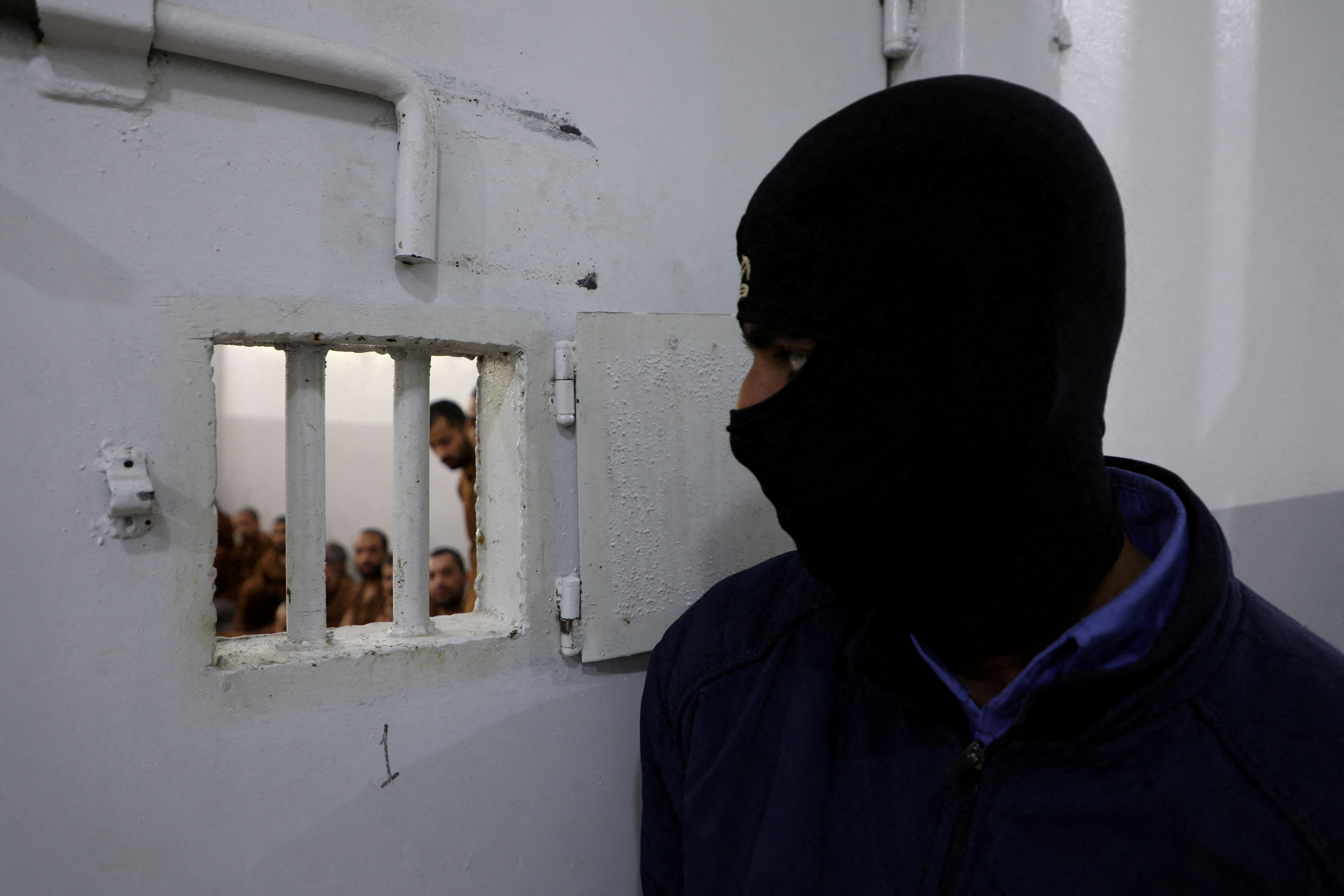 FILE PHOTO: A guard looks at Islamic State fighters at al-Sina'a prison in Hasakah