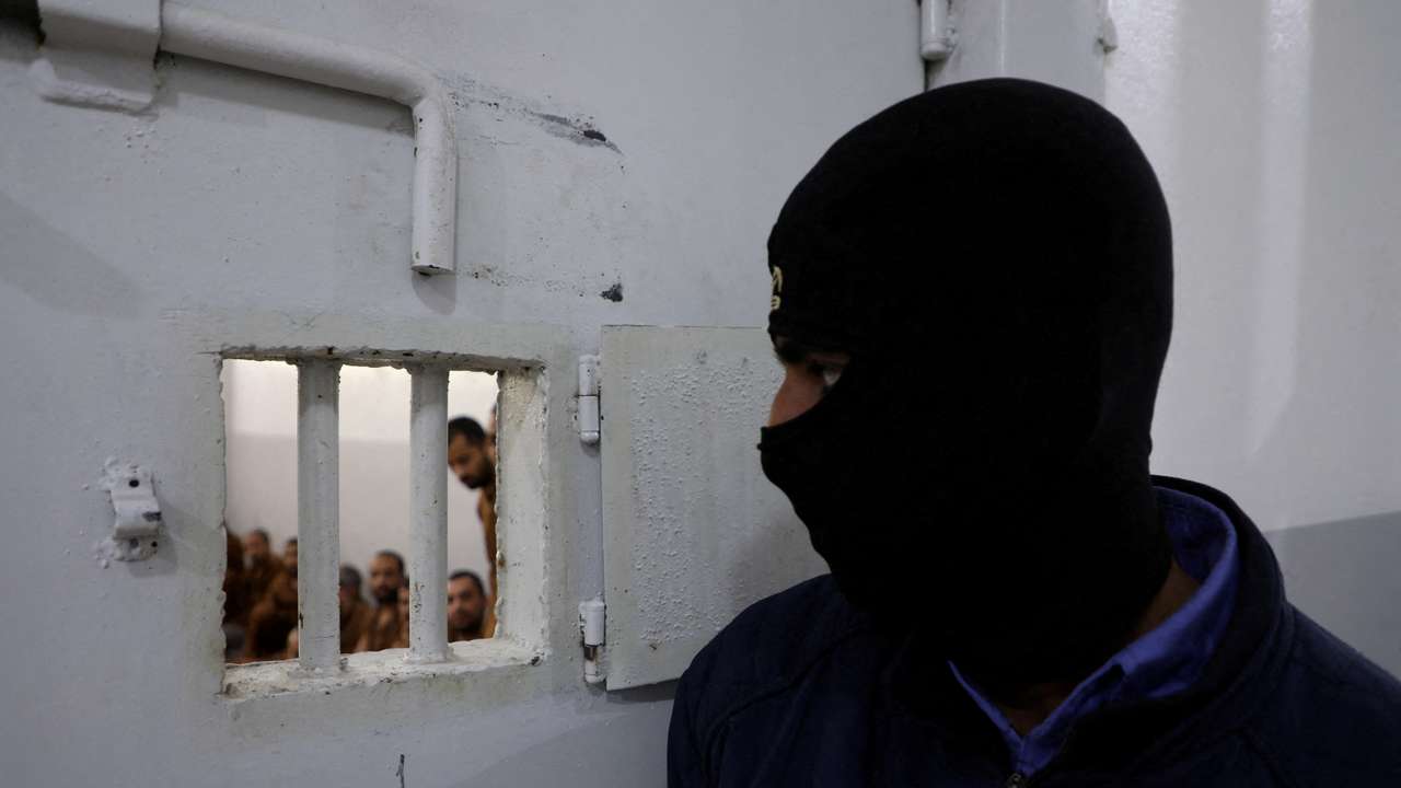 FILE PHOTO: A guard looks at Islamic State fighters at al-Sina'a prison in Hasakah
