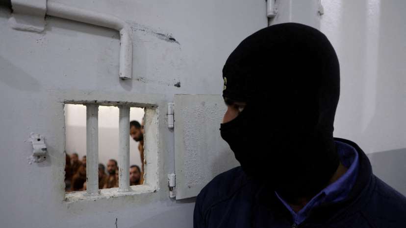FILE PHOTO: A guard looks at Islamic State fighters at al-Sina'a prison in Hasakah