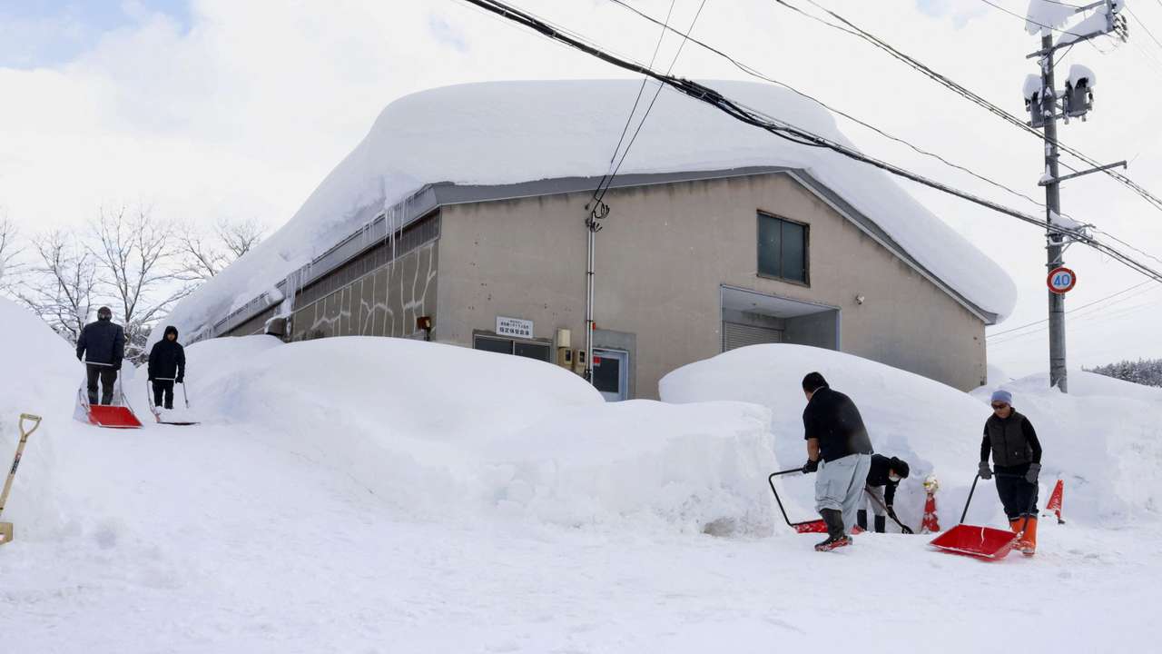 People remove snow near a house in Aomori, northeastern Japan, as heavy snow continues to hit the region
