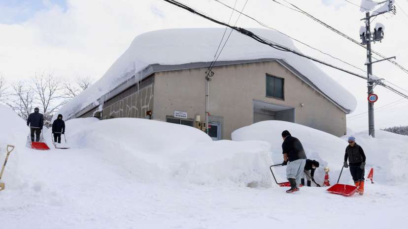 People remove snow near a house in Aomori, northeastern Japan, as heavy snow continues to hit the region