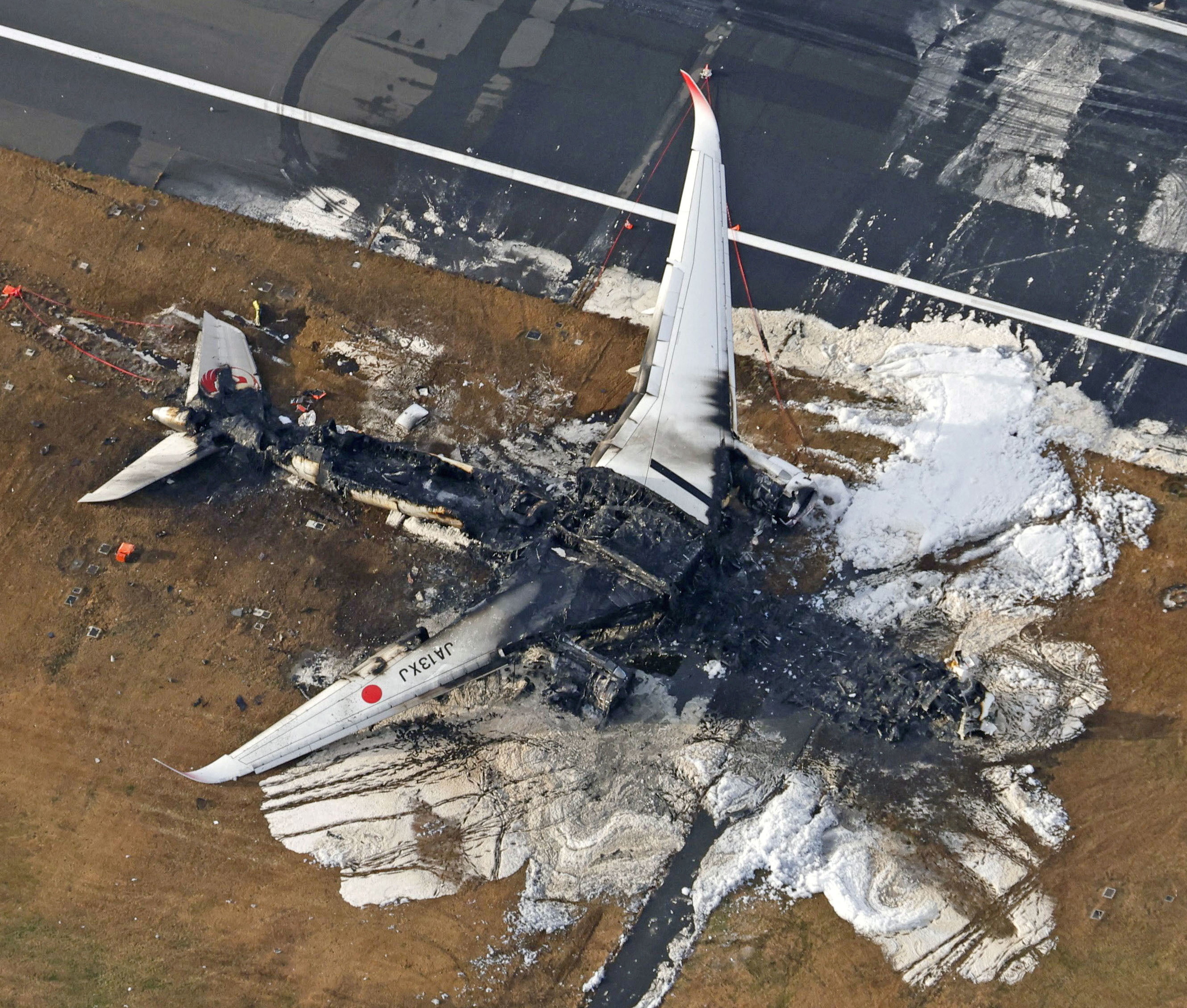 An aerial view shows burnt Japan Airlines' (JAL) Airbus A350 plane after a collision with a Japan Coast Guard aircraft at Haneda International Airport in Tokyo