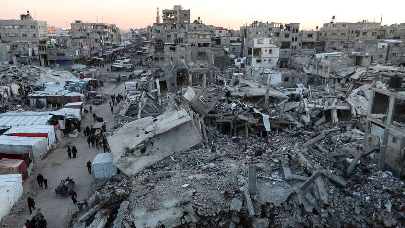 Palestinians walk among the rubble of buildings, In Khan Younis