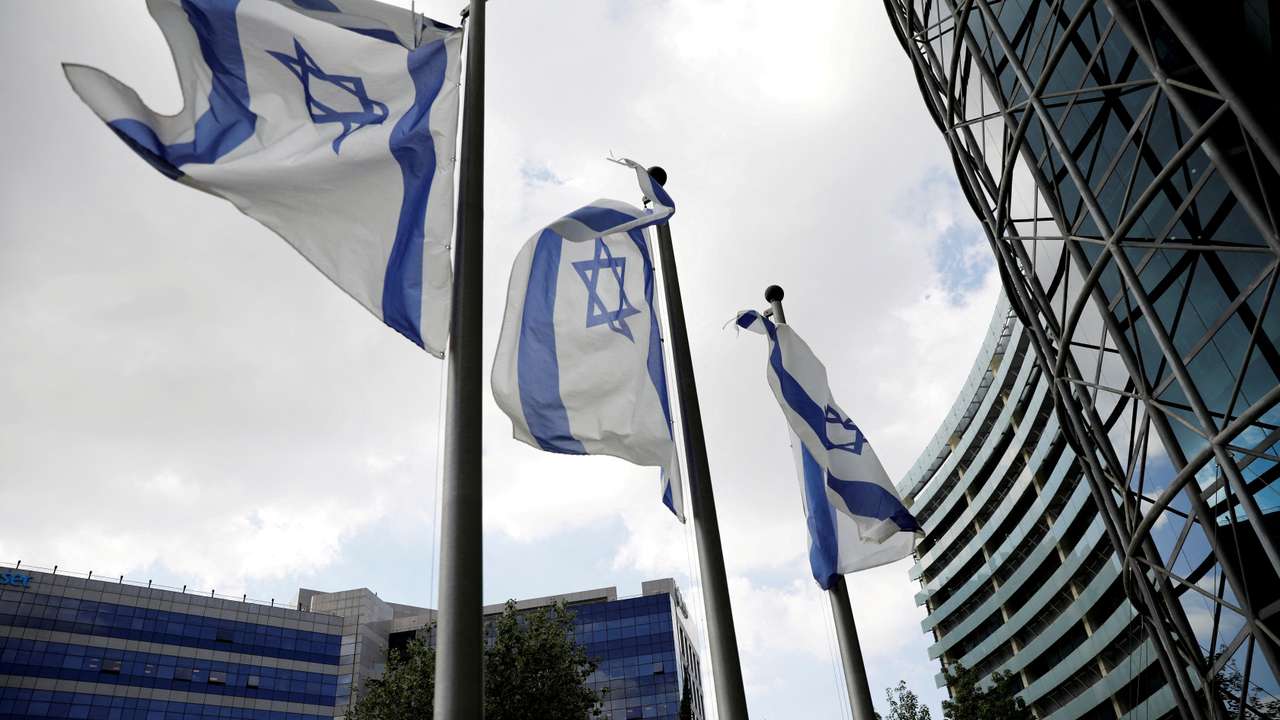 FILE PHOTO: Israeli national flags flutter near office towers at a business park in Petah Tikva, Israel