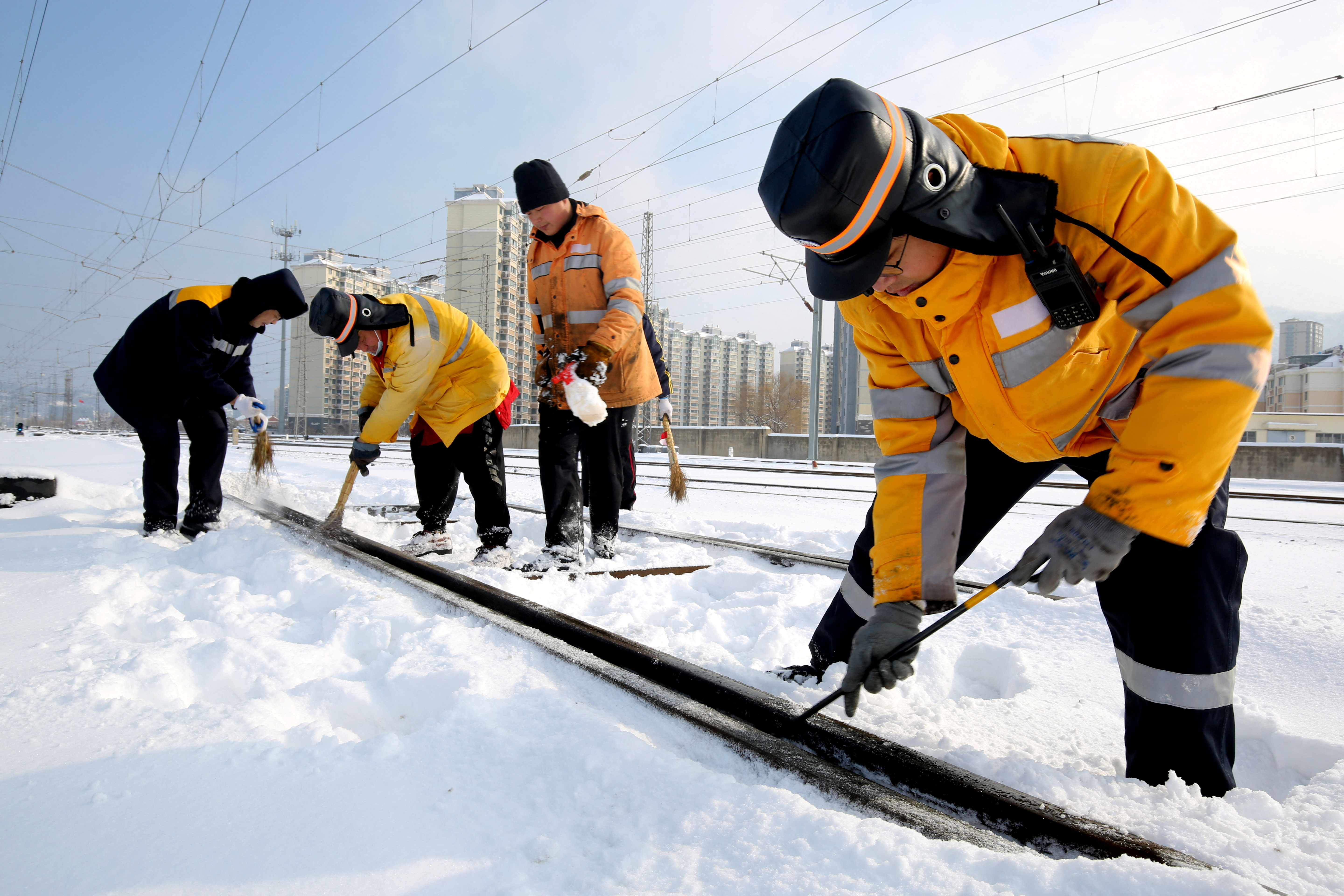 Workers clear ice and snow off the tracks along Lianyungang East railway station