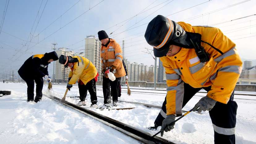Workers clear ice and snow off the tracks along Lianyungang East railway station