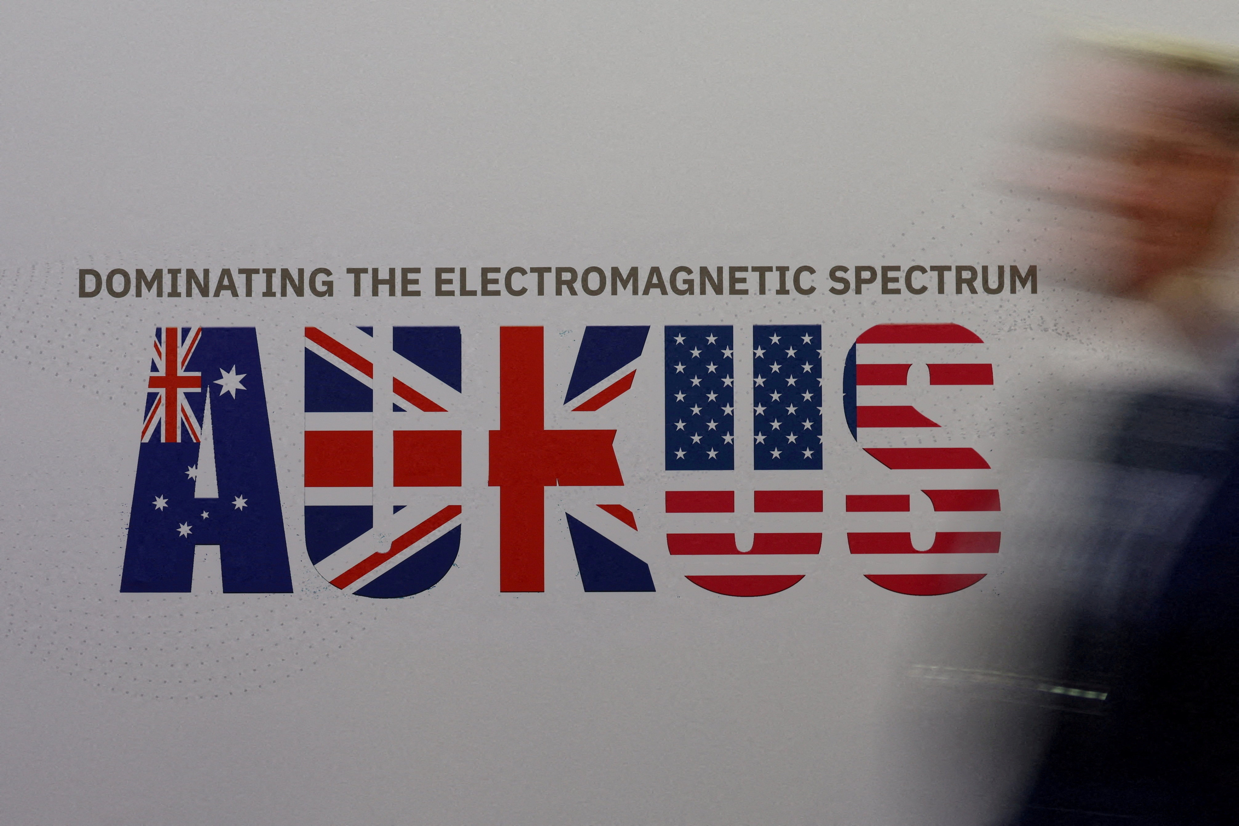 A man walks past an AUKUS sign at the Indo Pacific International Maritime Exposition in Sydney