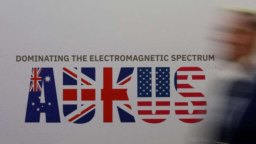 A man walks past an AUKUS sign at the Indo Pacific International Maritime Exposition in Sydney