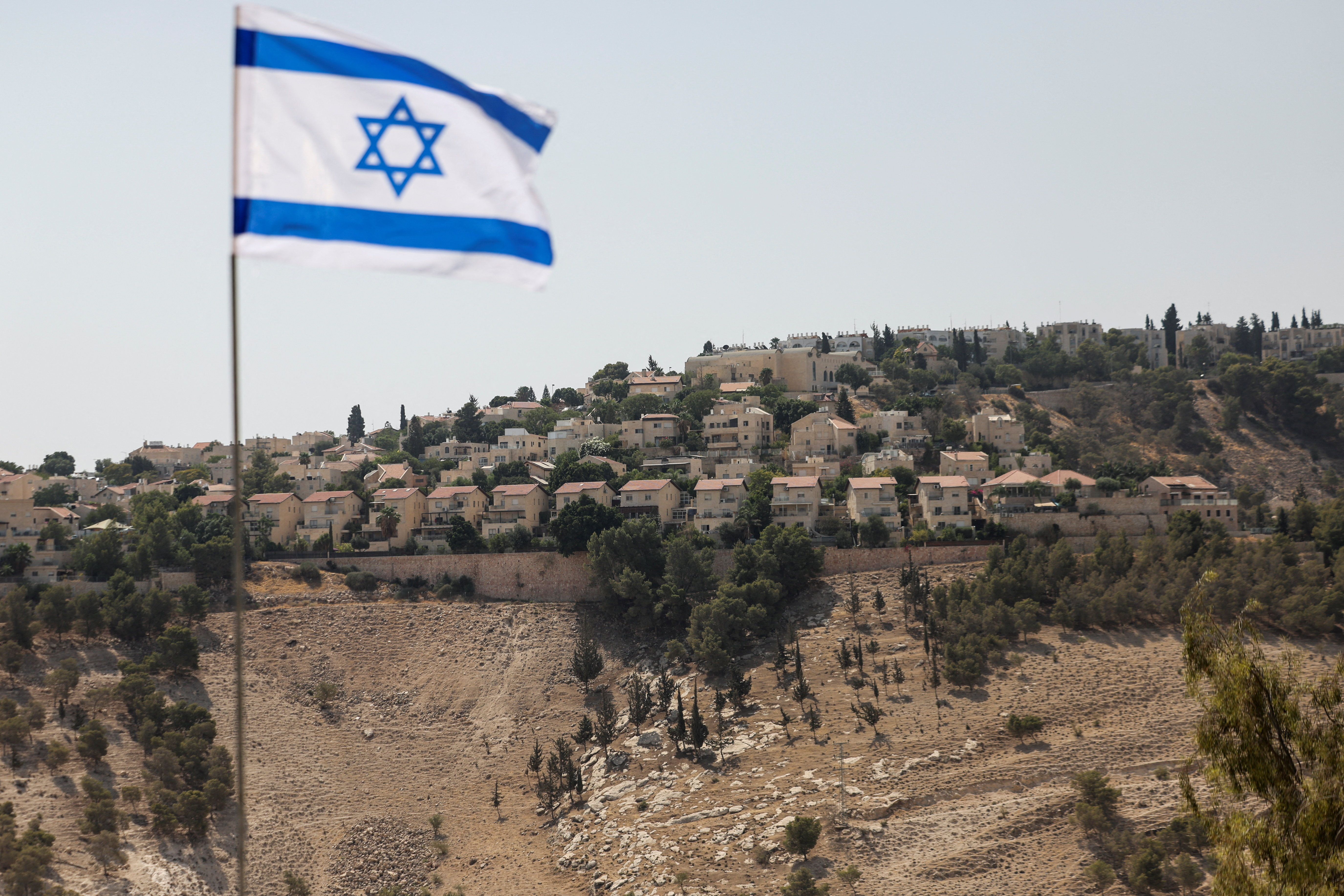 Israeli flag flutters, as part of the Israeli settlement of Maale Adumim is visible in the background, in the Israeli-occupied West Bank