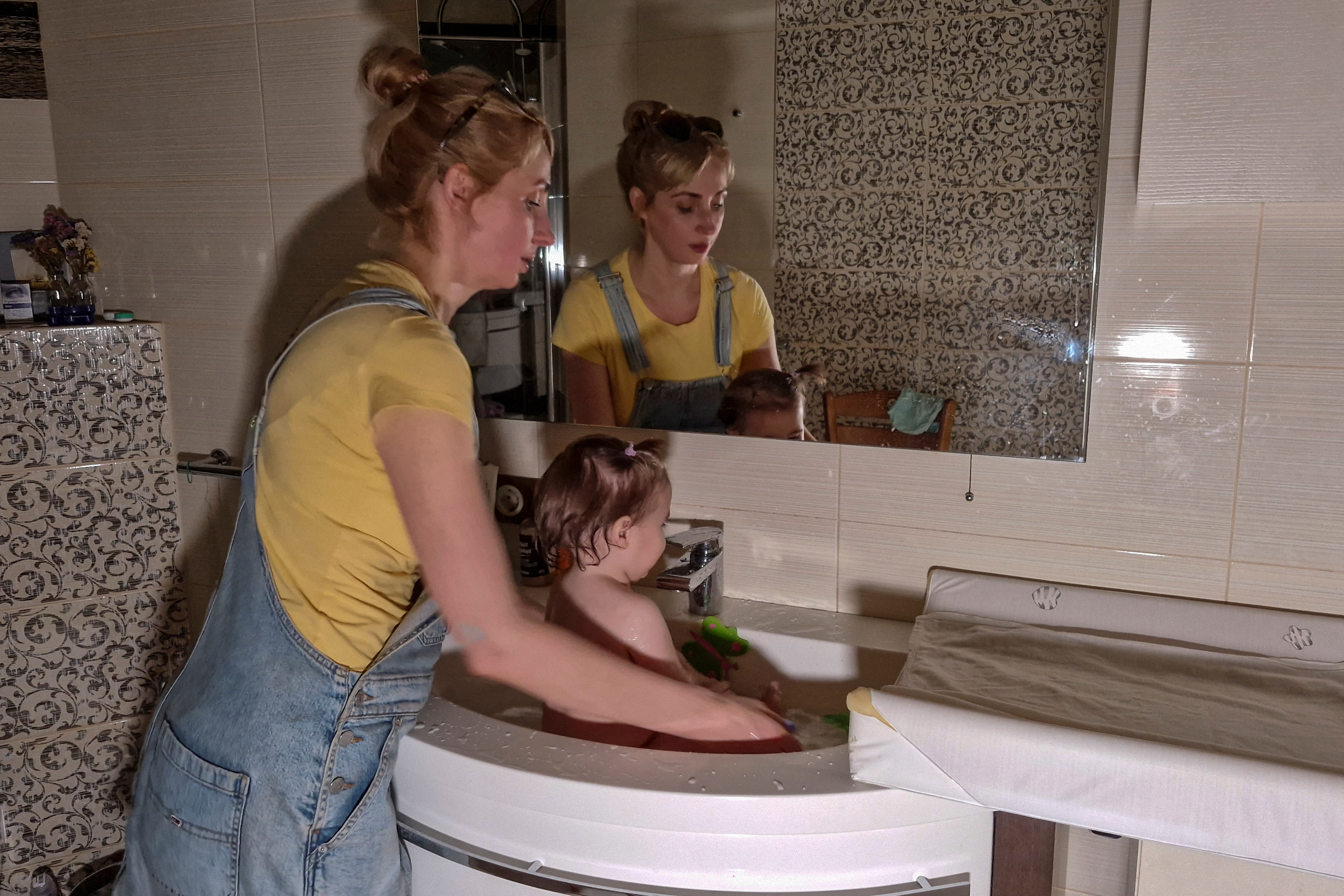 Woman cools 1-year-old daughter in a bathroom sink on an extremely hot day during power cuts in Kyiv
