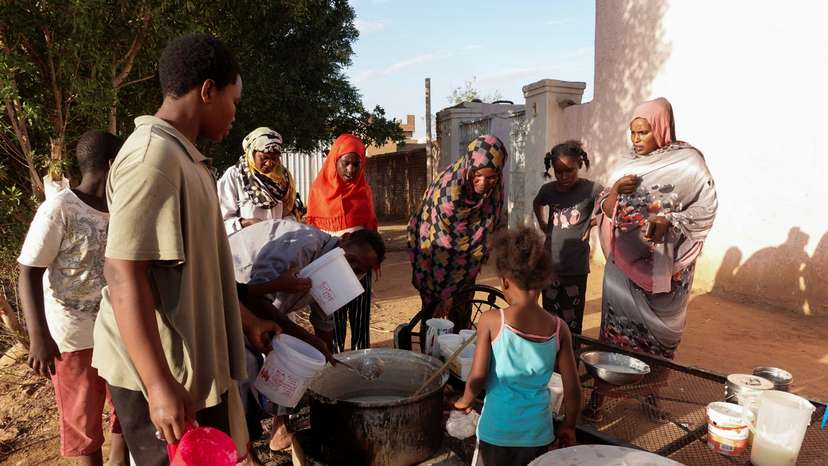 Displaced Sudanese families wait to receive food from a charity kitchen, in the city of Omdurman