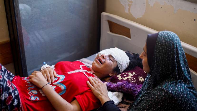 Palestinian girl Maisa Al-Ghandour, who was wounded in an Israeli strike along with her two siblings and mother, is comforted by her mother as she cries on a bed at Nasser hospital, in Khan Younis in the southern Gaza Strip