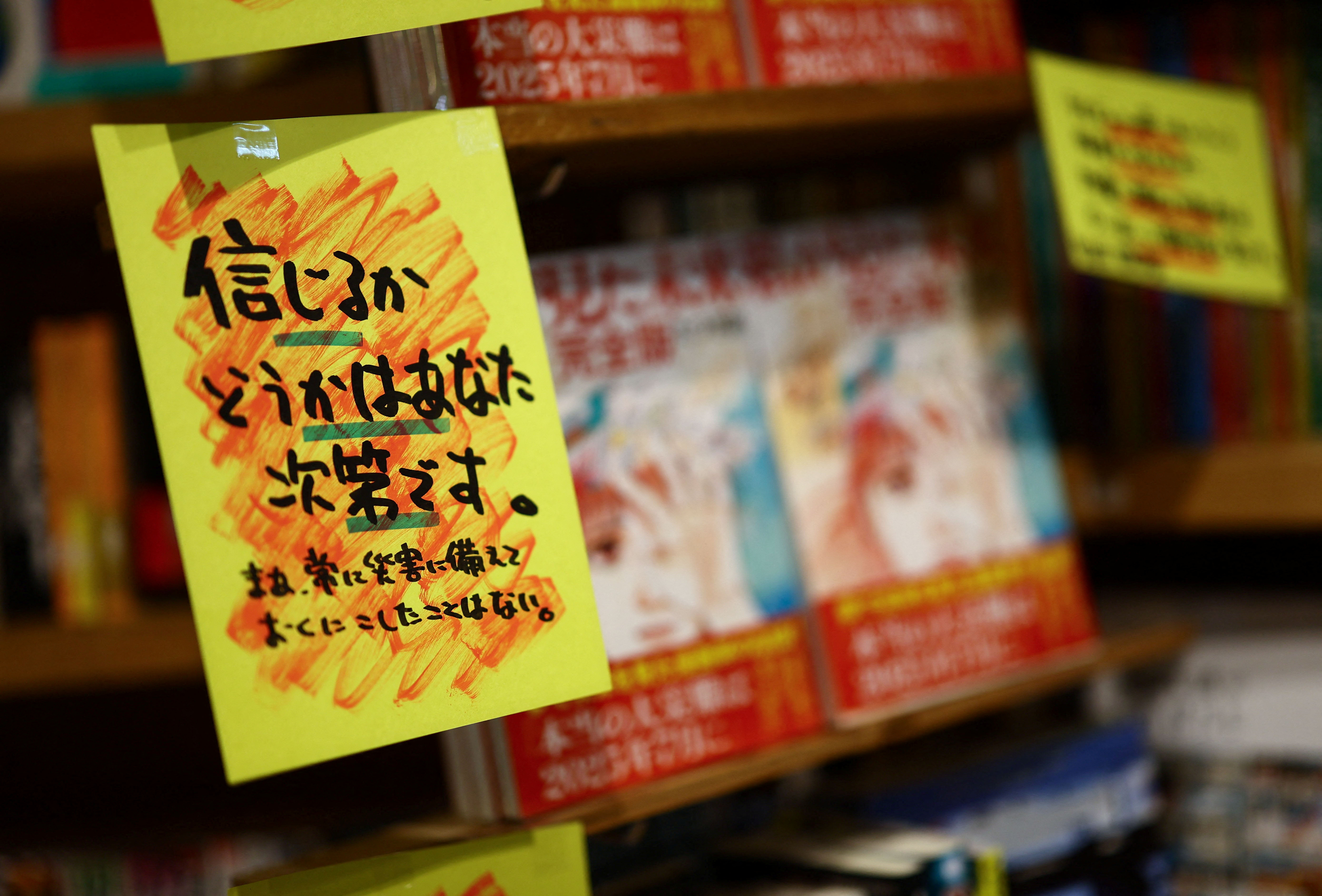 A sales banner written by the store reading 'Whether you believe it or not is up to you' is displayed next to the comic book titled 'The Future I saw' at Village Vanguard book store in Tokyo