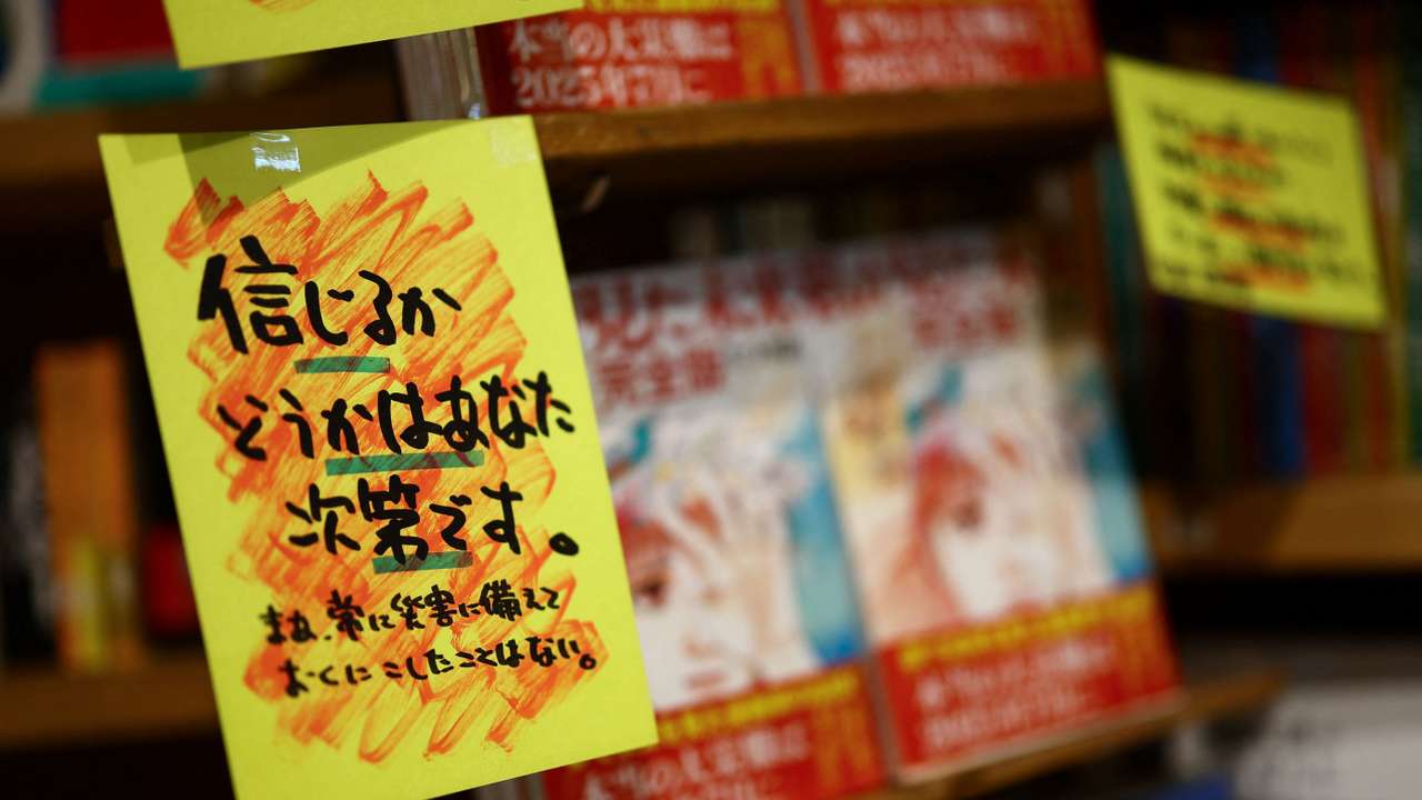 A sales banner written by the store reading 'Whether you believe it or not is up to you' is displayed next to the comic book titled 'The Future I saw' at Village Vanguard book store in Tokyo