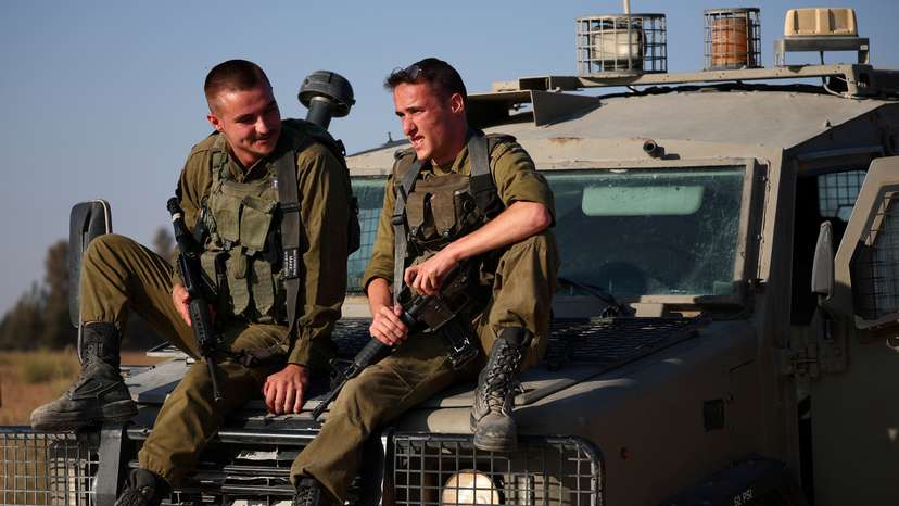 Israeli soldiers sit on a military vehicle near the Israel-Gaza border, amid the Israel-Hamas conflict