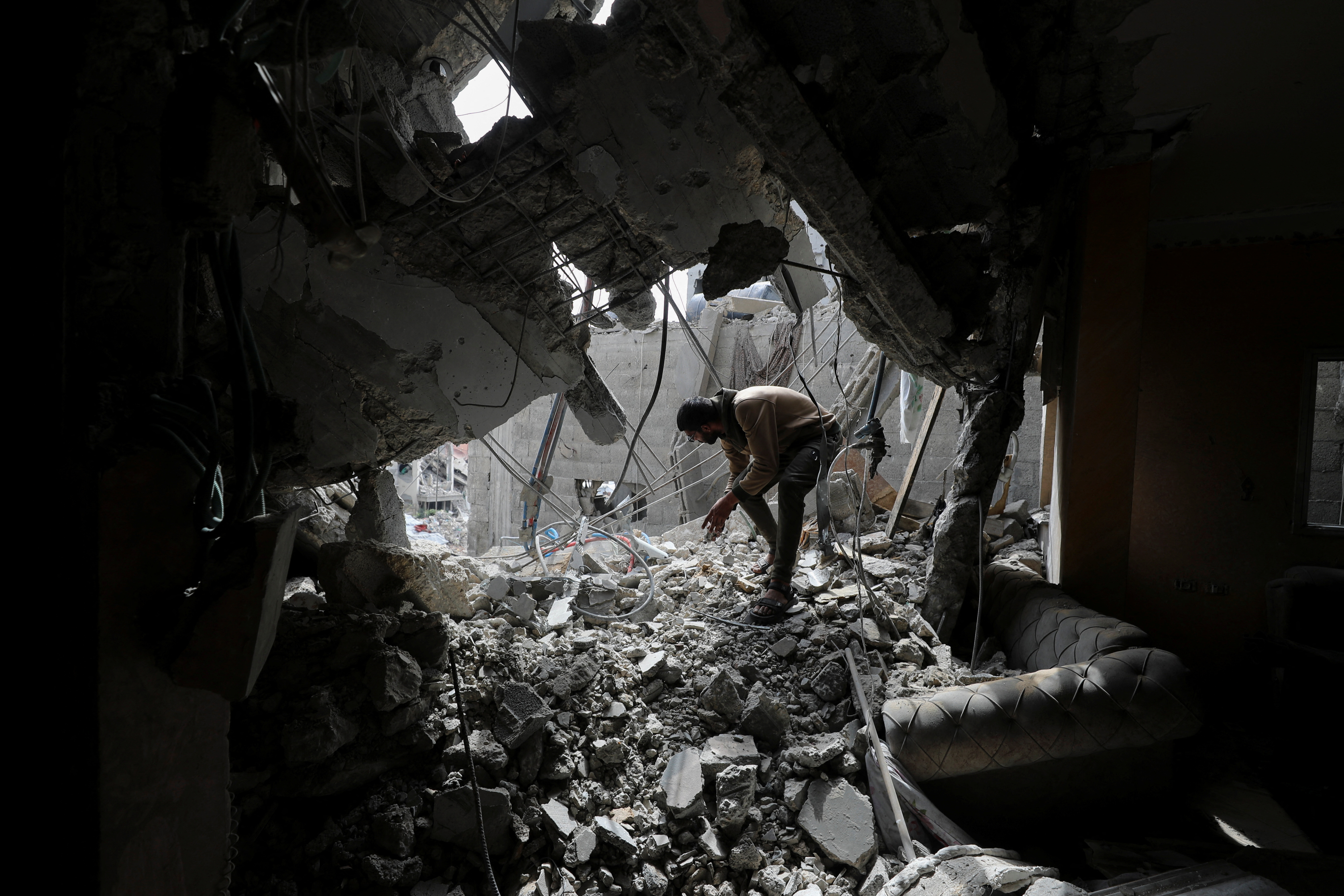 Palestinians inspect the site of an Israeli strike on a house, in Gaza City