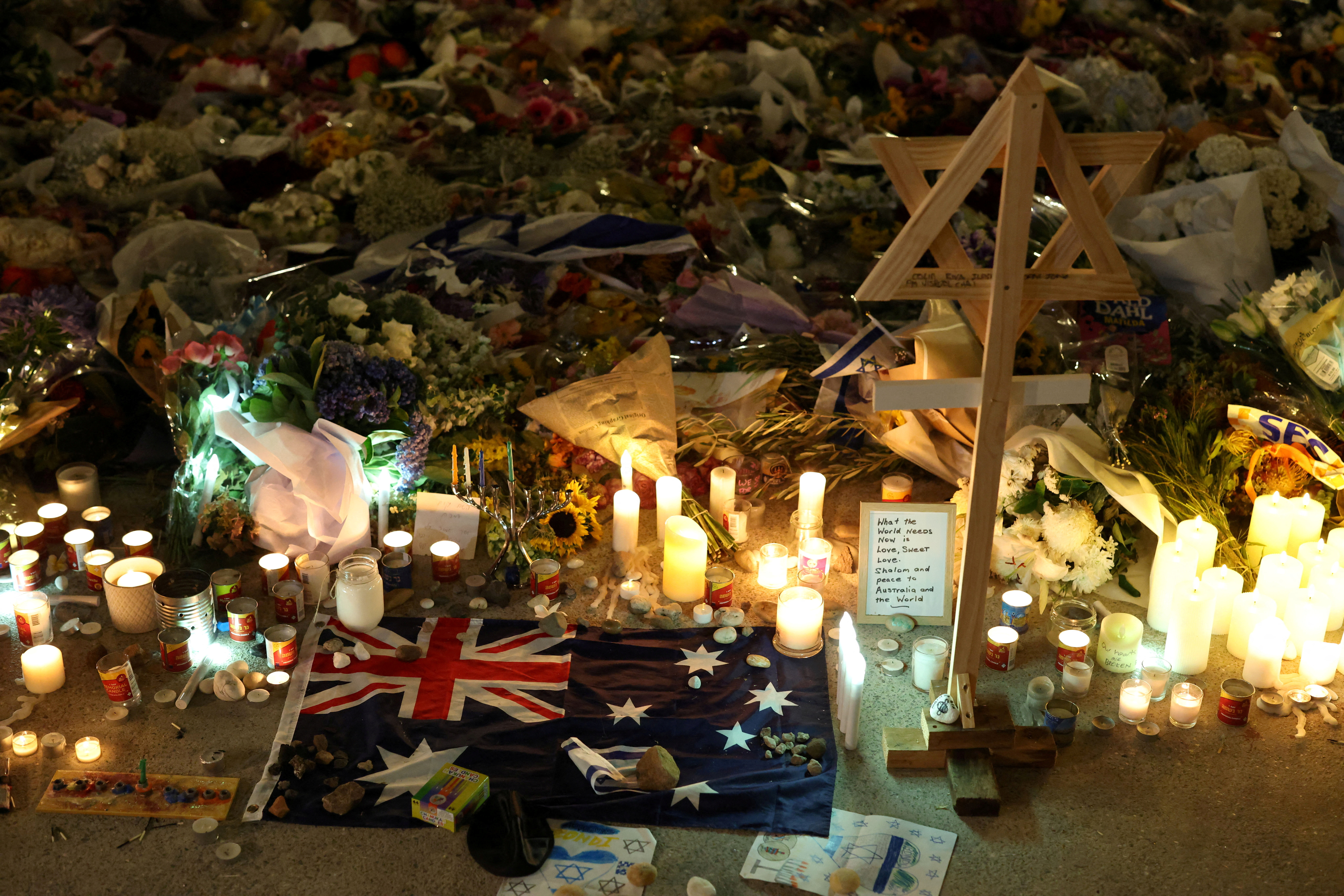 FILE PHOTO: An Australian flag sits amongst floral tributes honouring the victims of a shooting at Jewish holiday celebration on Sunday at Bondi Beach, in Sydney