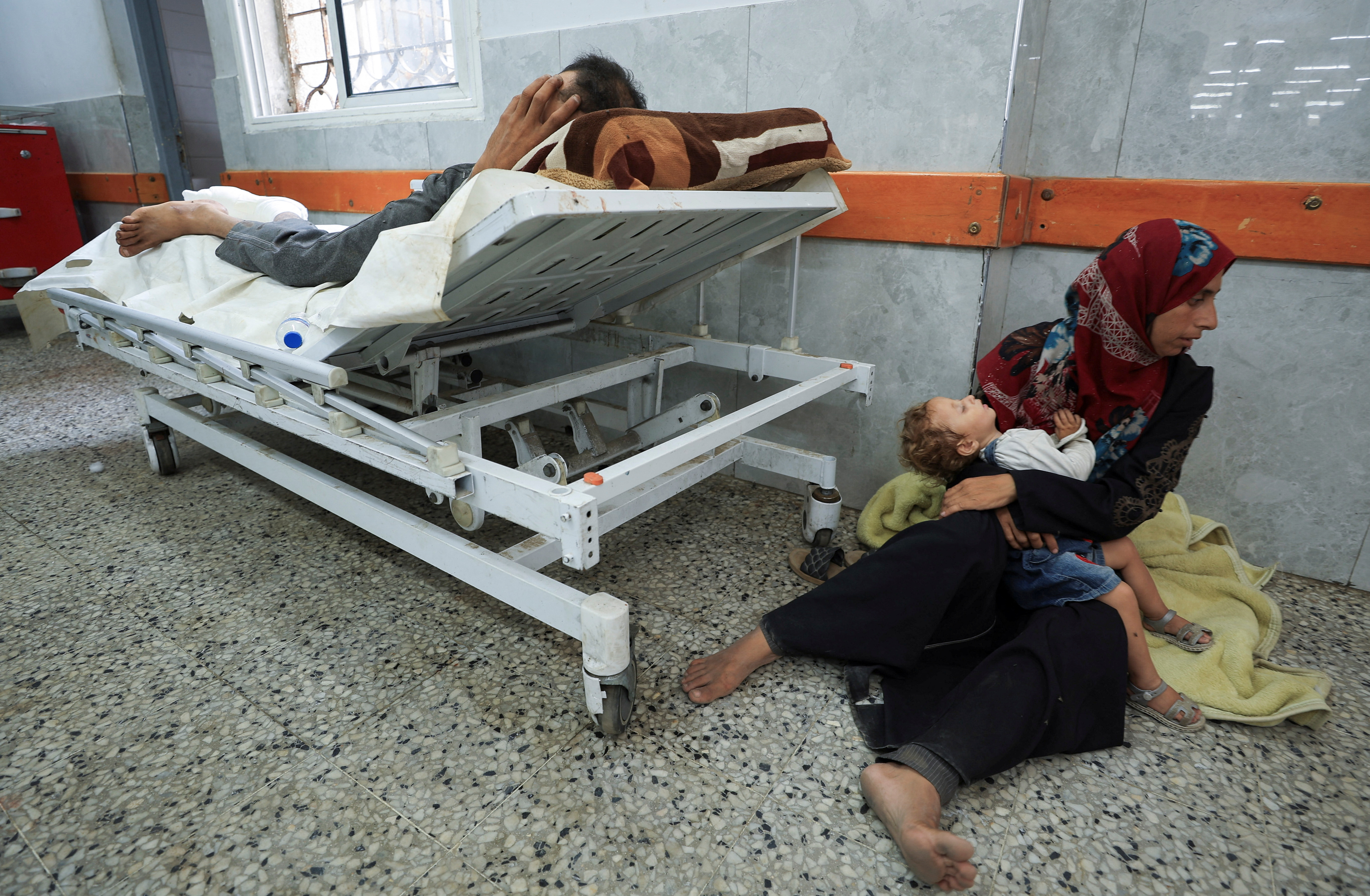 A Palestinian wounded in Israeli fire near an aid distribution center in central Gaza, according to medics, lies at Al-Shifa hospital, in Gaza City