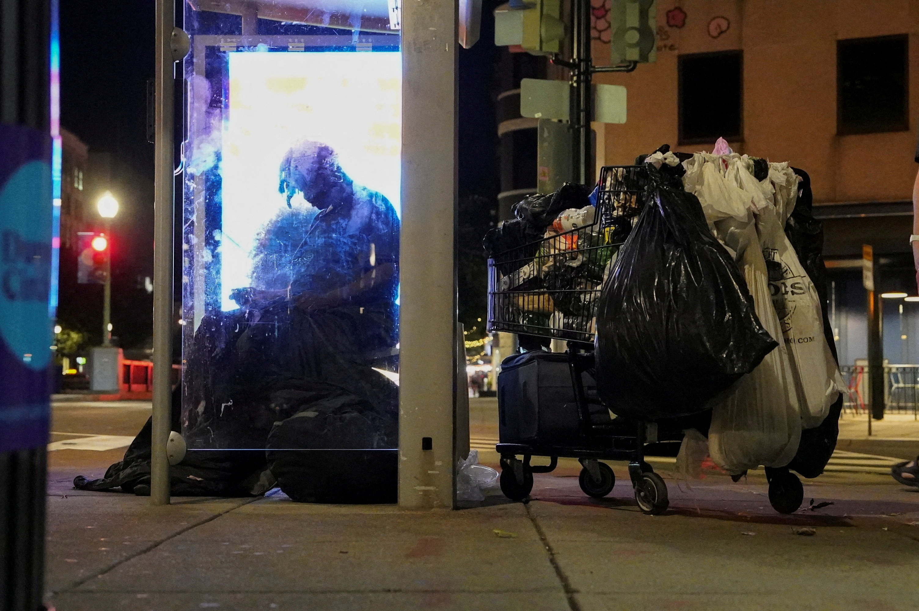 FILE PHOTO: A homeless person sits at a bustop in Dupont Circle, in Washington