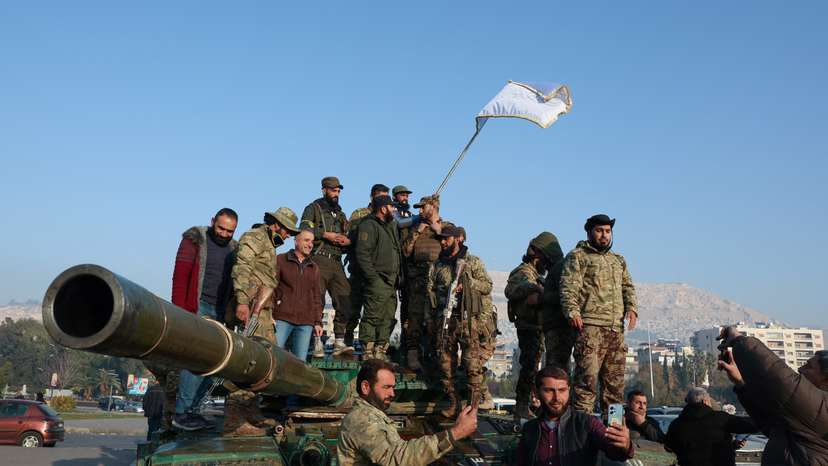 Rebel fighters stand on a tank,, in Damascus