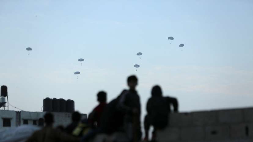 People watch as U.S. military carries out its first aid drop over Gaza, amid the ongoing the conflict between Israel and the Palestinian Islamist group Hamas, in Gaza City