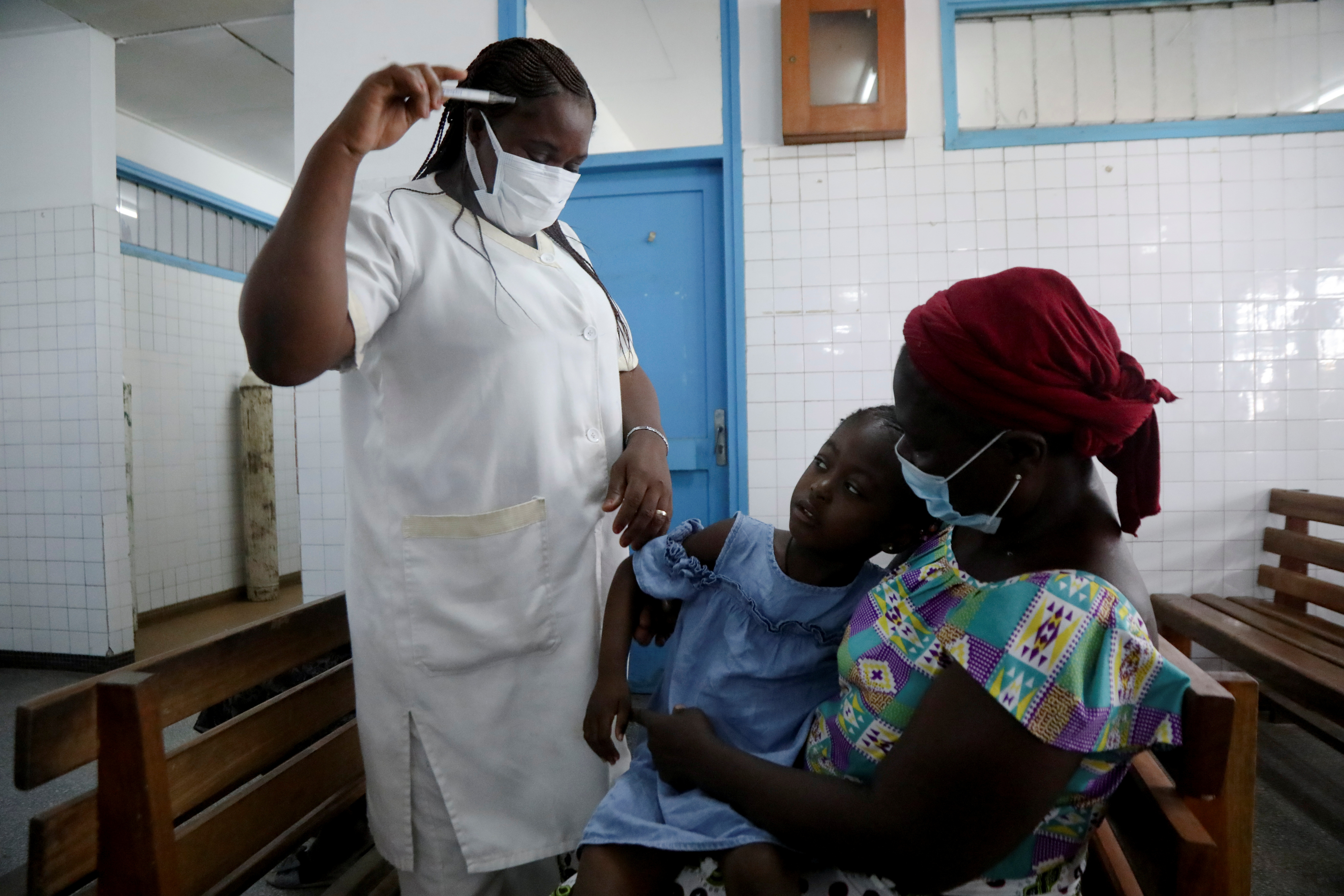 A nurse prepares to take the temperature of a child with malaria at Marcory General Hospital in Abidjan