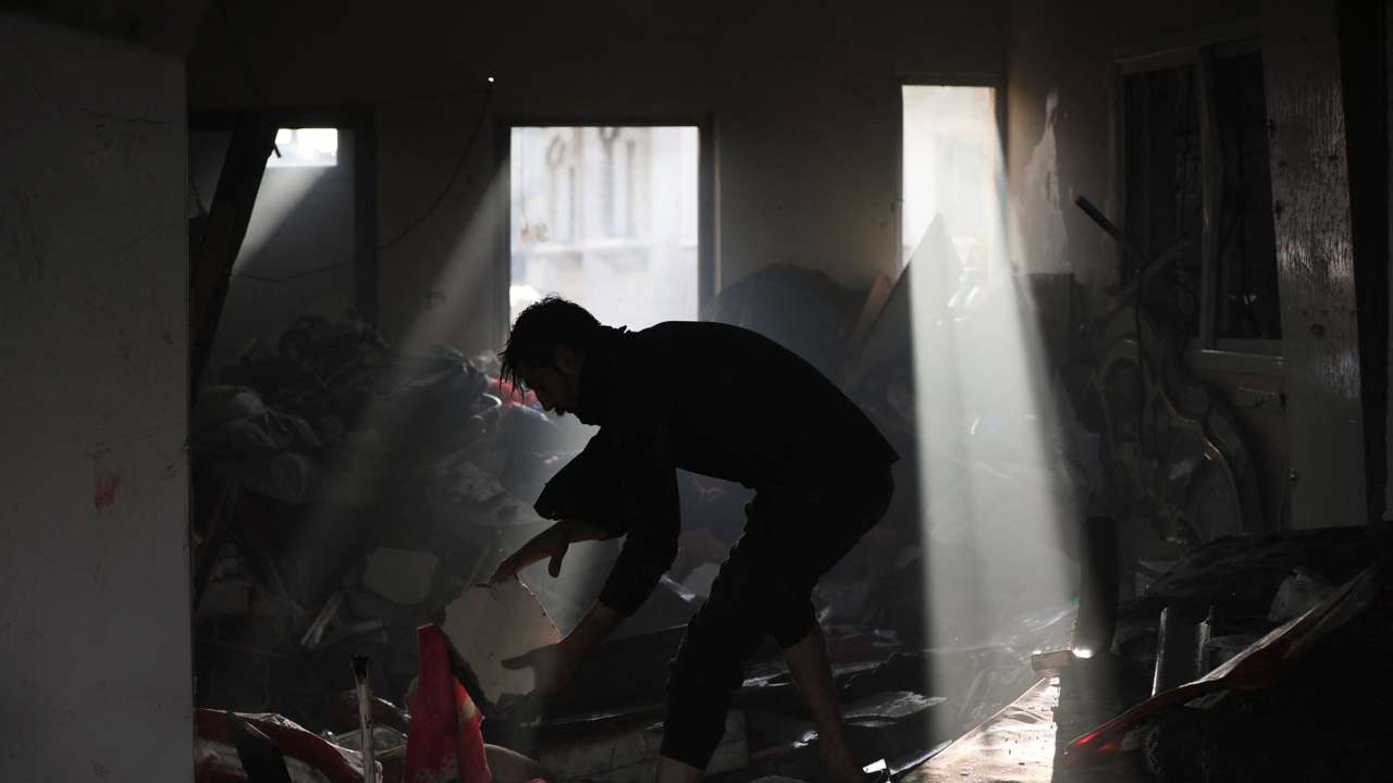 Palestinian picks up debris on the site of an Israeli strike at Maghazi refugee camp in the central Gaza Strip