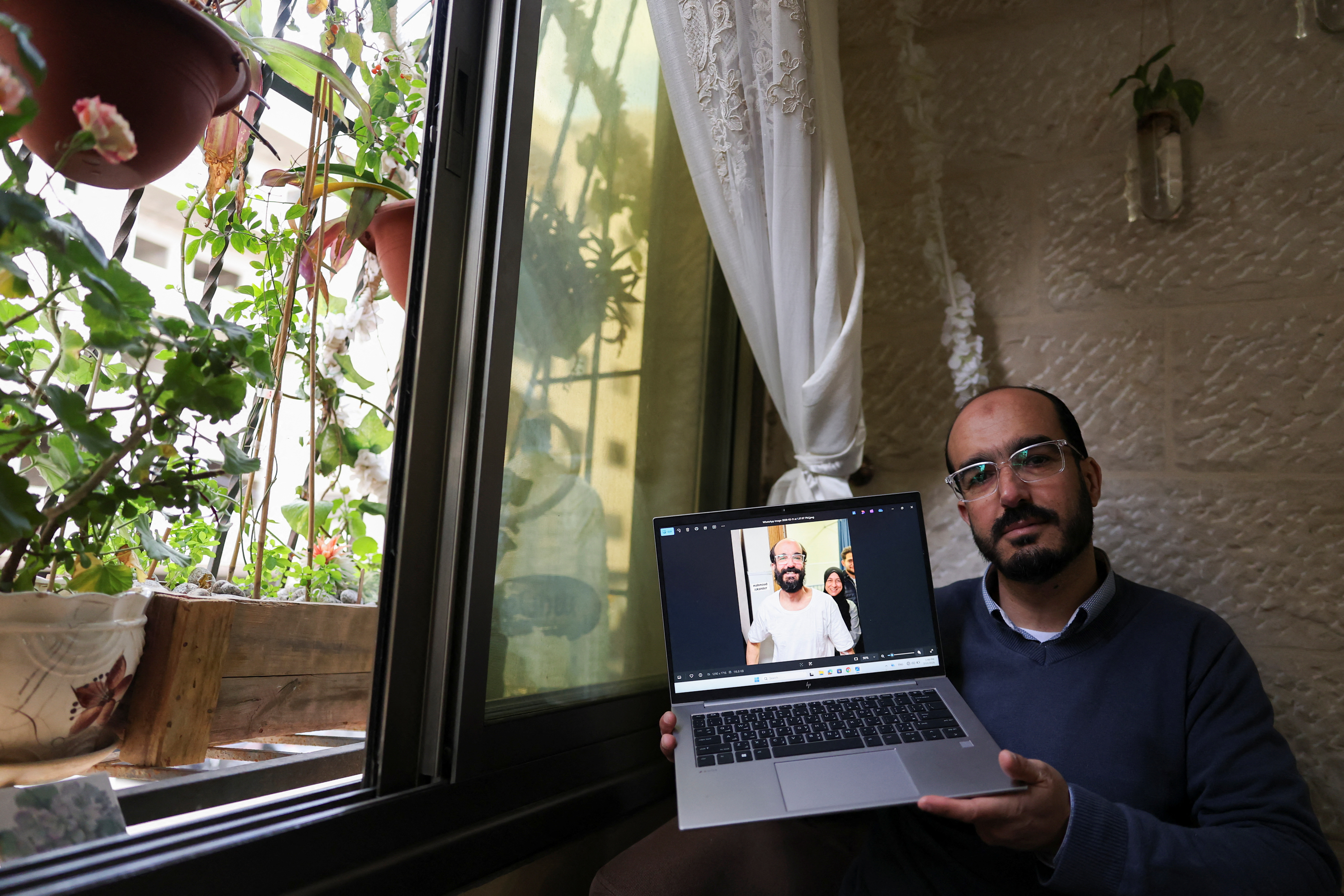 Samer Khaweireh, 45, shows a photo of how he appeared the day he was released from prison four weeks ago after he said he lost 22 kilos of weight in nine months, as he sits in his home in Nablus