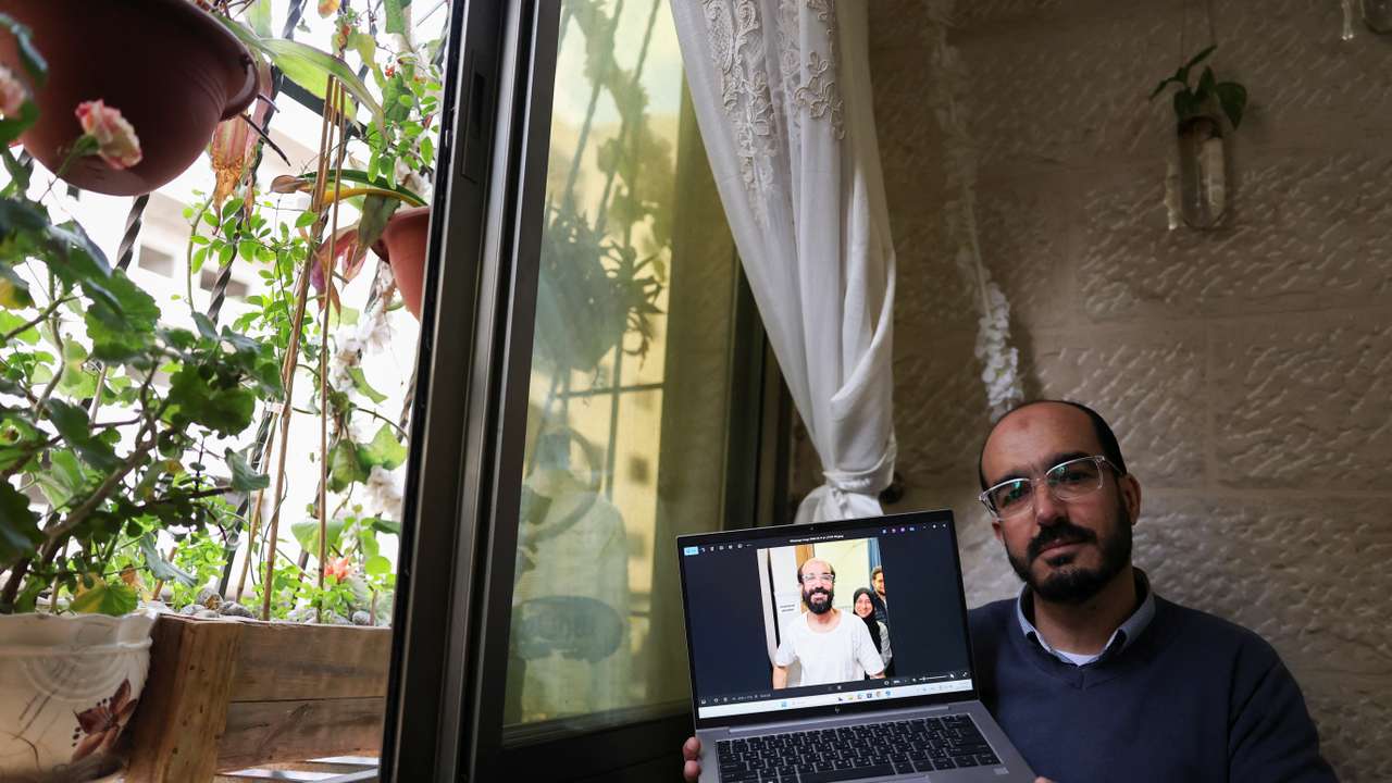 Samer Khaweireh, 45, shows a photo of how he appeared the day he was released from prison four weeks ago after he said he lost 22 kilos of weight in nine months, as he sits in his home in Nablus