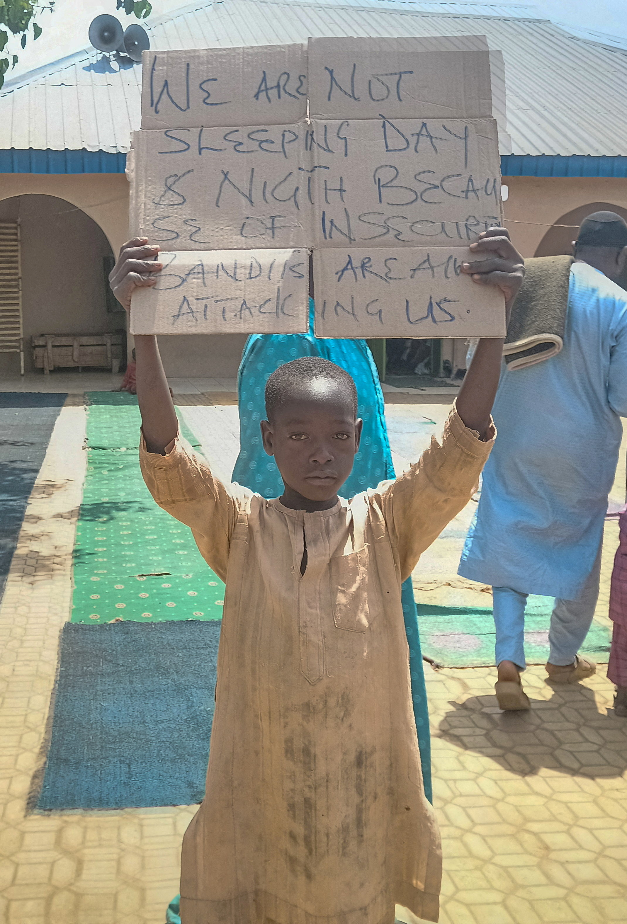 FILE PHOTO: A boy holds a sign to protest against, what a teacher, local councilor and parents said, the kidnapping of hundreds school pupils by gunmen after the Friday prayer, in Kaduna