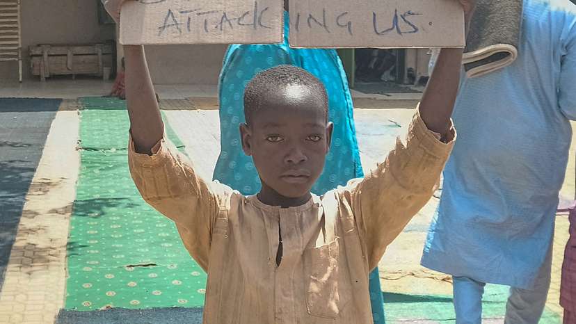 FILE PHOTO: A boy holds a sign to protest against, what a teacher, local councilor and parents said, the kidnapping of hundreds school pupils by gunmen after the Friday prayer, in Kaduna