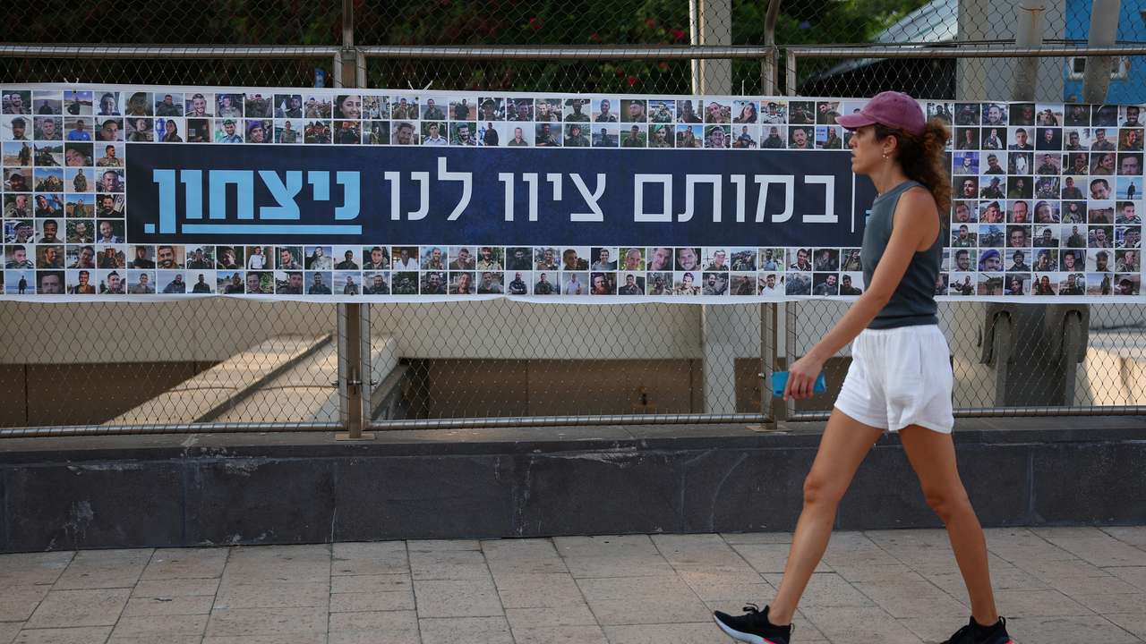 A woman walks past a banner depicting the faces of Israel’s fallen soldiers, amid the ongoing conflict in Gaza between Israel and Hamas, in Tel Aviv