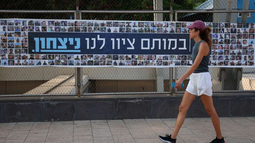 A woman walks past a banner depicting the faces of Israel’s fallen soldiers, amid the ongoing conflict in Gaza between Israel and Hamas, in Tel Aviv
