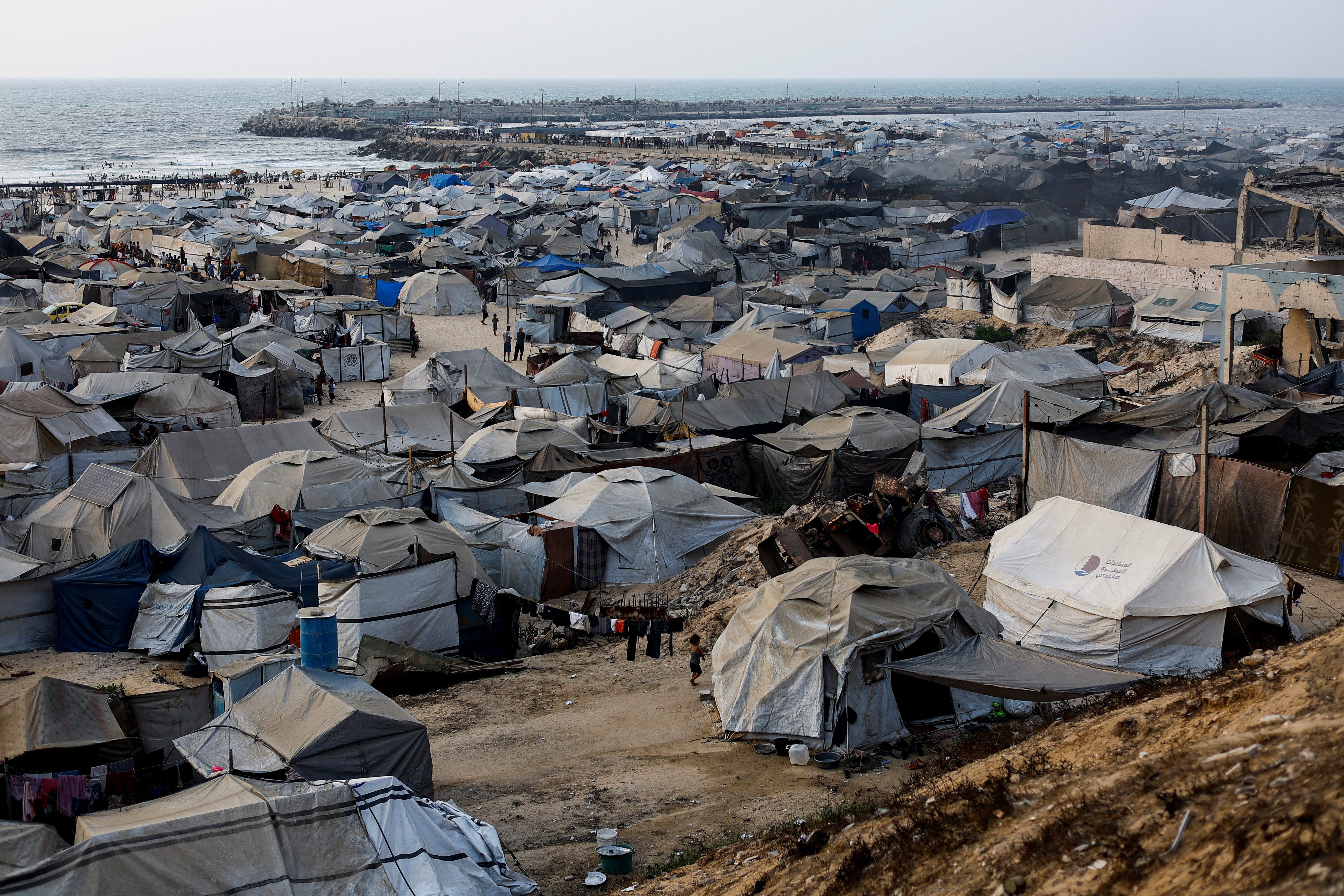 Palestinians displaced by the Israeli offensive shelter in a tent camp on a beach amid summer heat in Gaza City