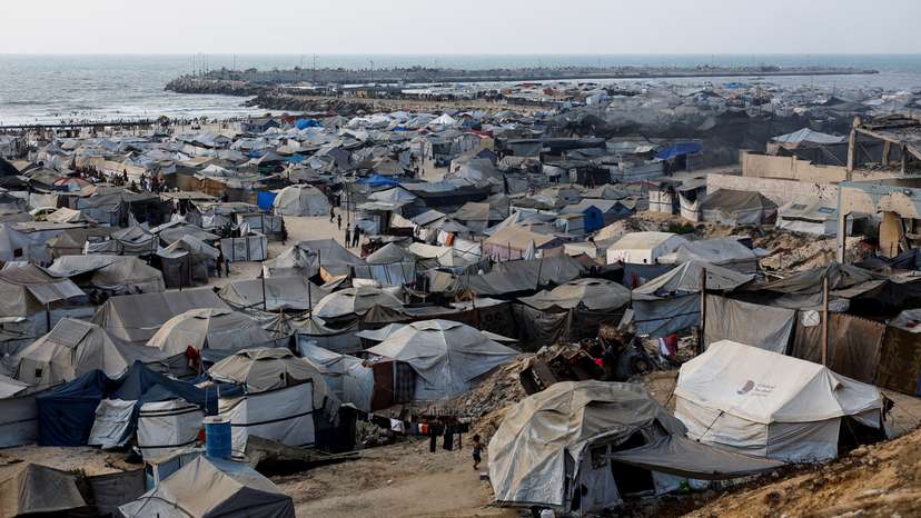 Palestinians displaced by the Israeli offensive shelter in a tent camp on a beach amid summer heat in Gaza City