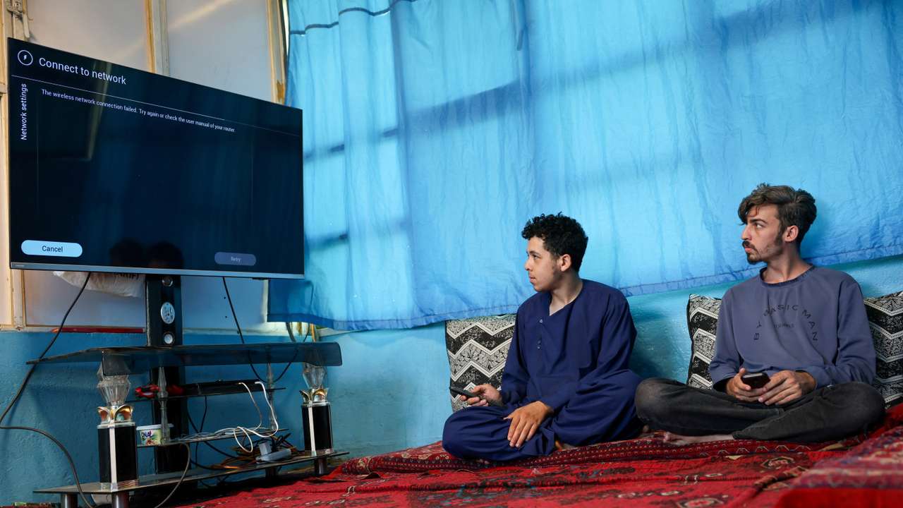 Men try to connect their smart TV to the internet inside their home, amid telecom shutdown across the country, in Kabul