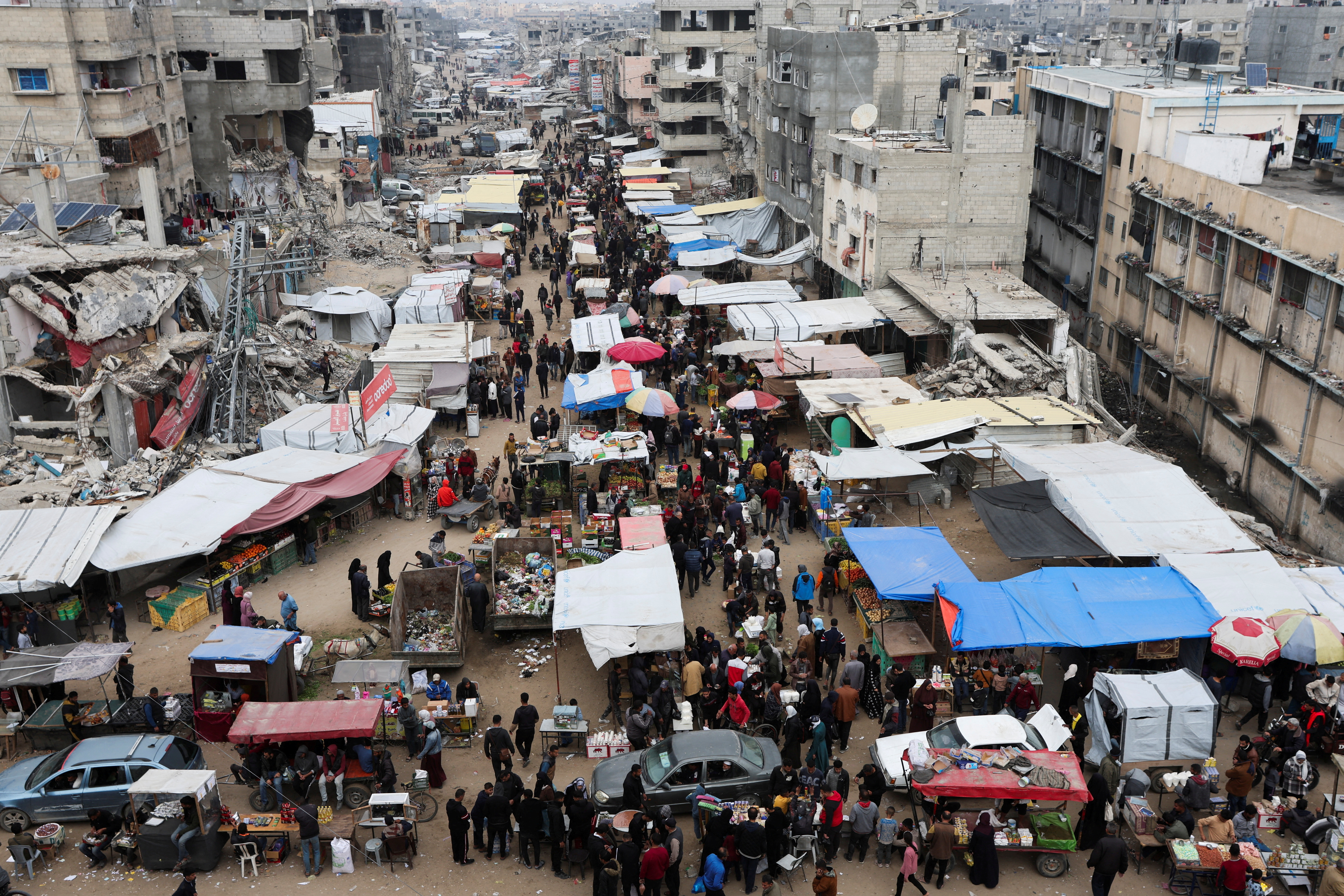 Palestinians walk on a street market amid ceasefire negotiations, in Khan Younis in the southern Gaza Strip