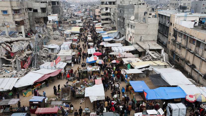 Palestinians walk on a street market amid ceasefire negotiations, in Khan Younis in the southern Gaza Strip