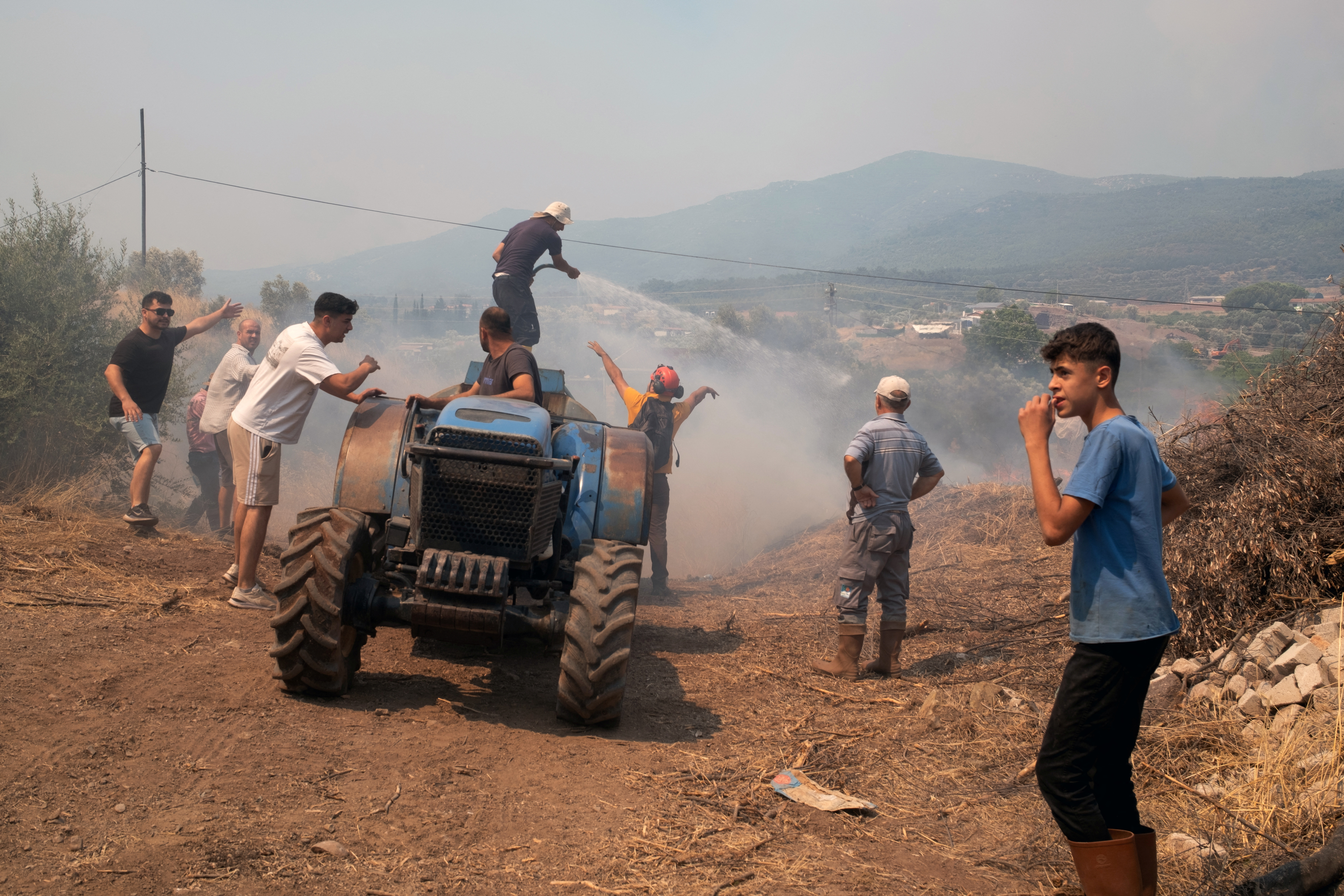 People respond to a wildfire in a village near Seferihisar in Izmir province