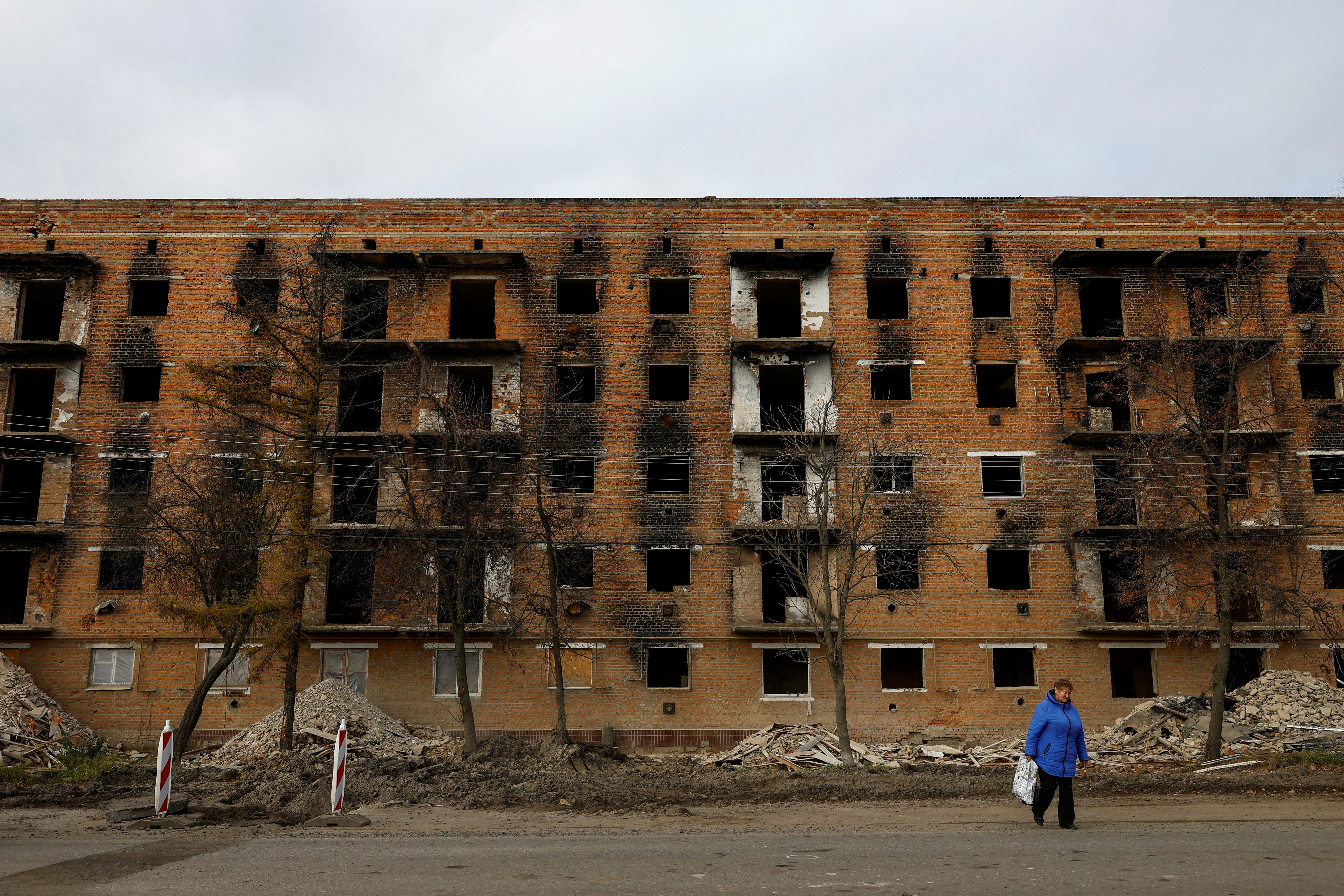 A local woman walks in front of an apartment building under reconstruction in the town of Trostianets