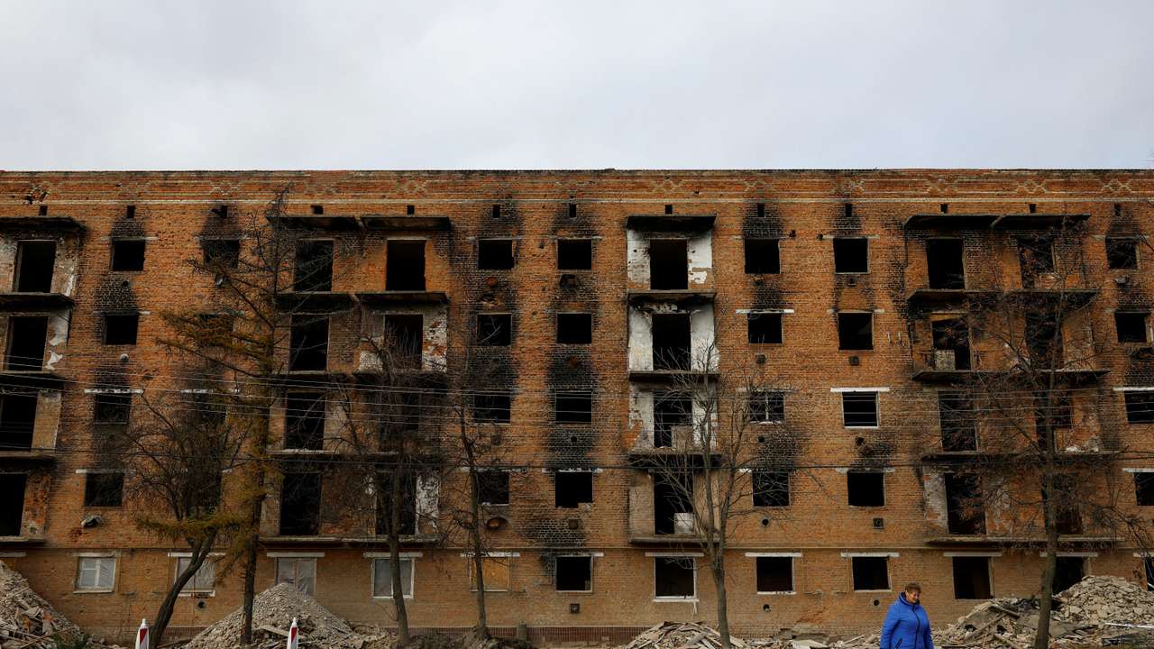 A local woman walks in front of an apartment building under reconstruction in the town of Trostianets