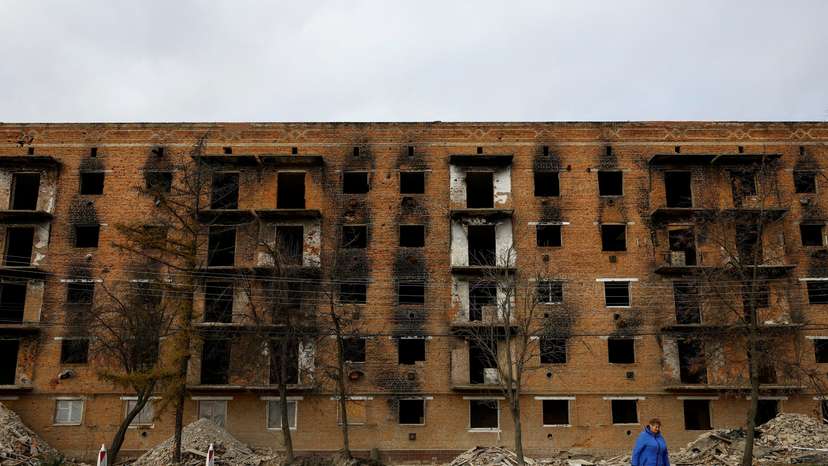 A local woman walks in front of an apartment building under reconstruction in the town of Trostianets