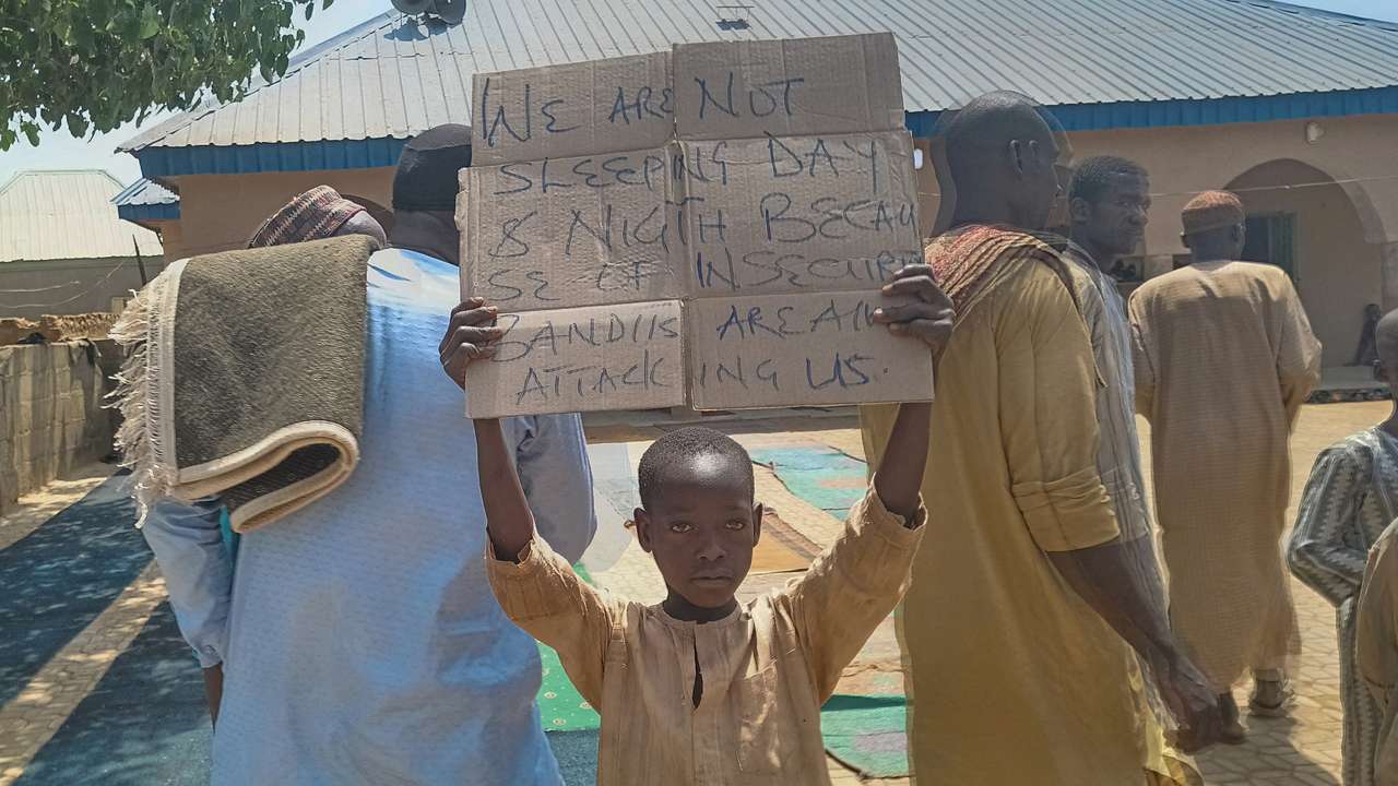 FILE PHOTO: A boy holds a sign to protest against, what a teacher, local councilor and parents said, the kidnapping of hundreds school pupils by gunmen after the Friday prayer, in Kaduna