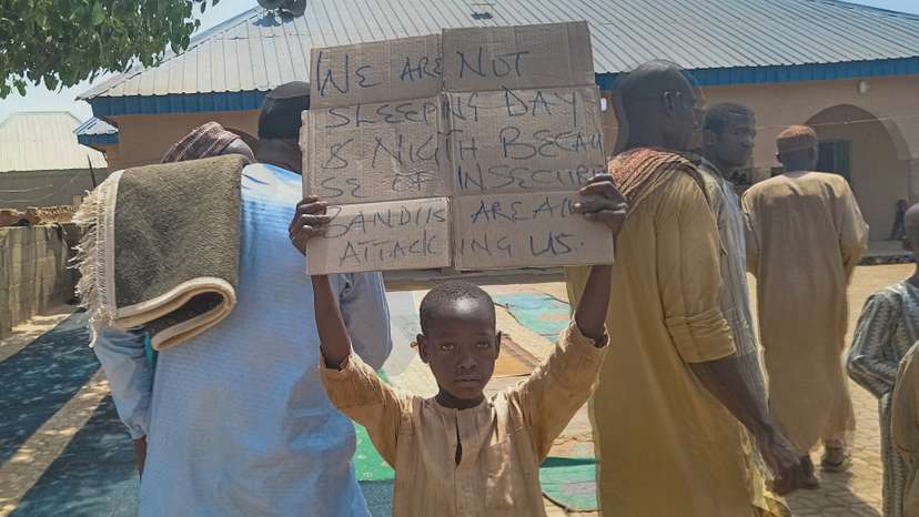 FILE PHOTO: A boy holds a sign to protest against, what a teacher, local councilor and parents said, the kidnapping of hundreds school pupils by gunmen after the Friday prayer, in Kaduna