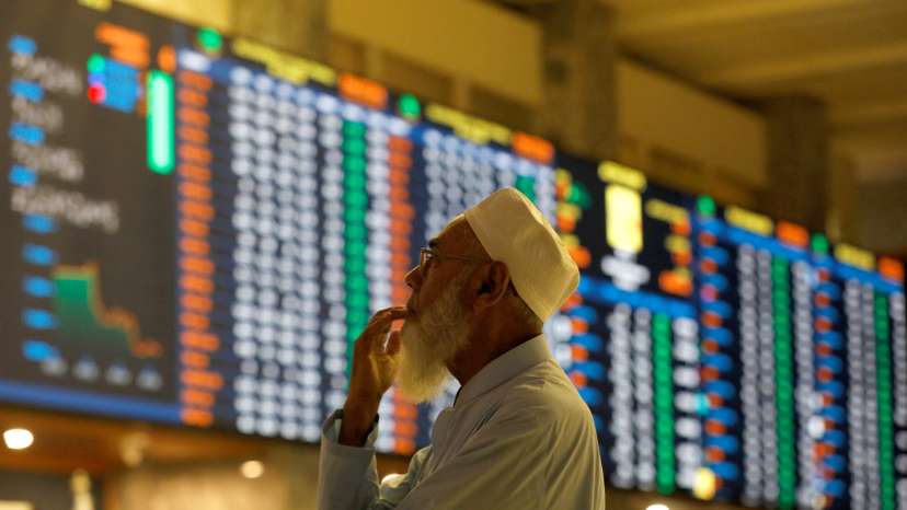 Stock broker monitors the market on the electronic board displaying share prices at the Pakistan Stock Exchange, in Karachi