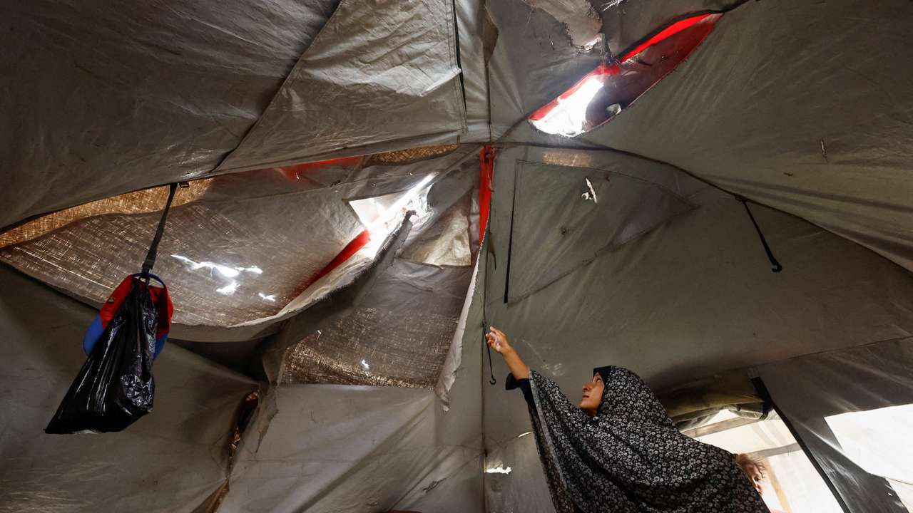 A displaced Palestinian woman shows her torn tent, amid a ceasefire between Israel and Hamas, in Gaza City