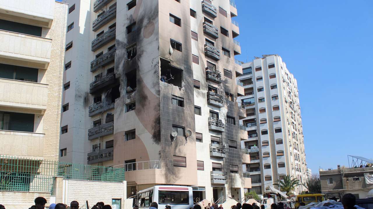 People gather near a damaged building in the Kafr Sousa district of Damascus