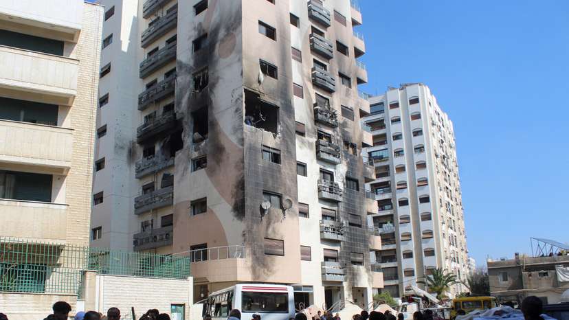 People gather near a damaged building in the Kafr Sousa district of Damascus
